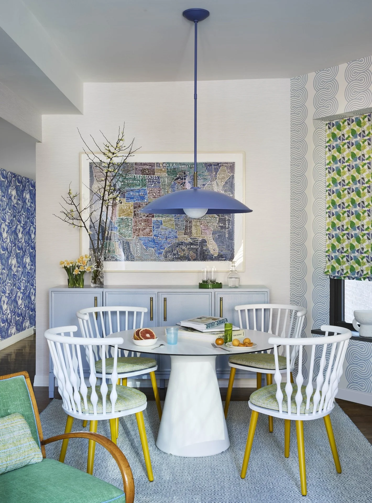 colorful modern dining room blue pendant light round white table geometric wallpaper bright chairs map art