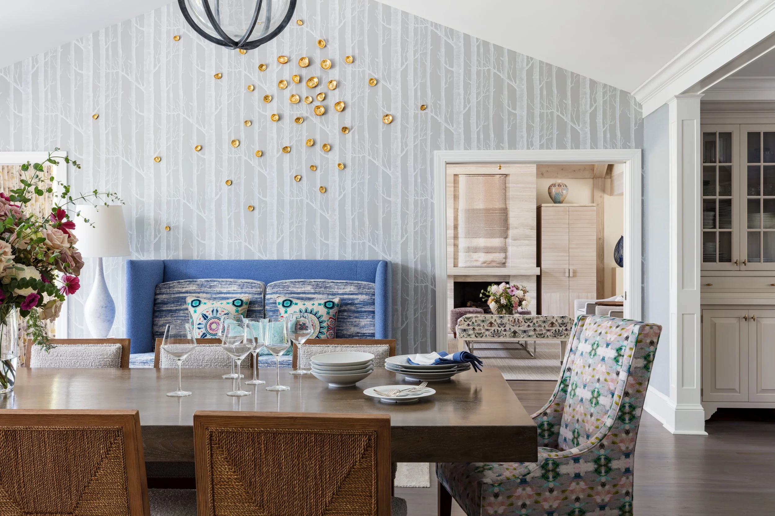 stylish dining room interior design with blue banquette and tree patterned wallpaper