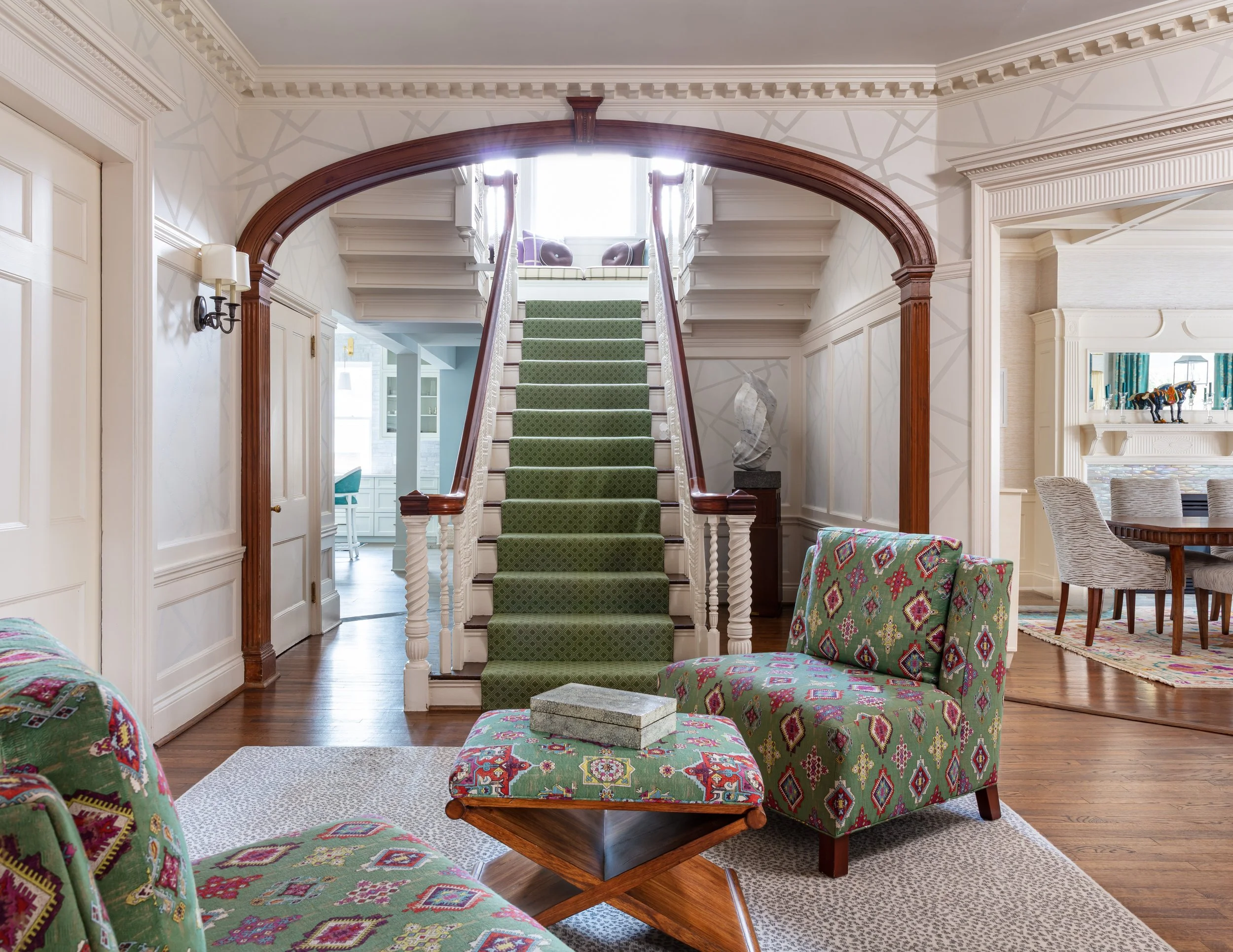 traditional entry with green stair runner cozy chairs ottoman and geometric wallpaper