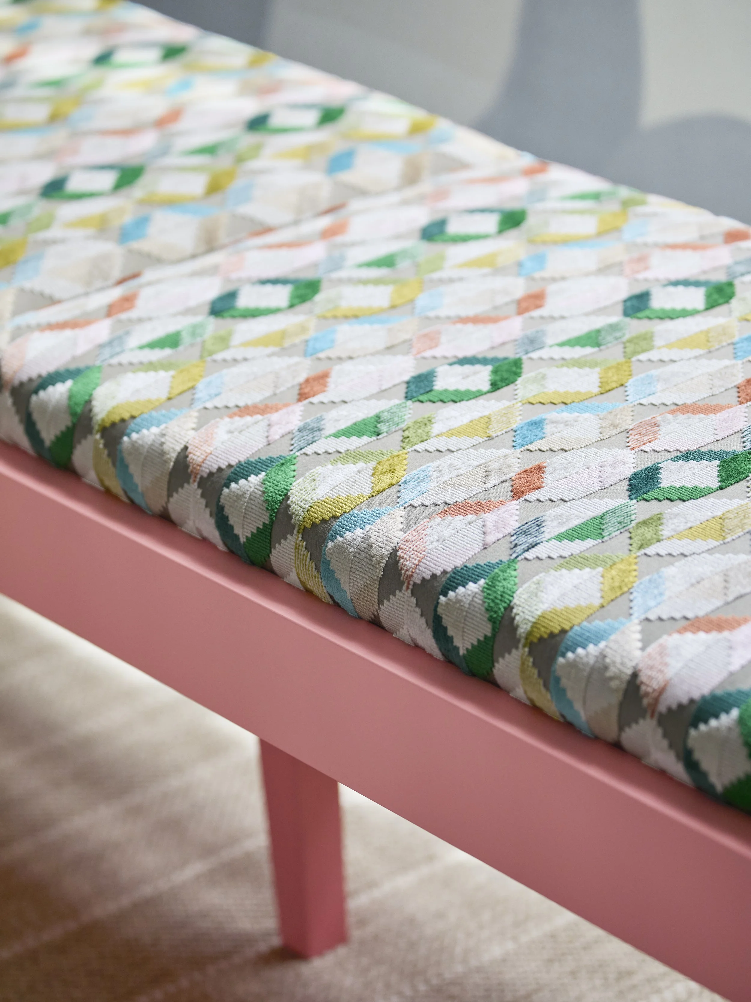 Pink upholstered bench with colorful geometric fabric in bright window nook by Betsy Wentz