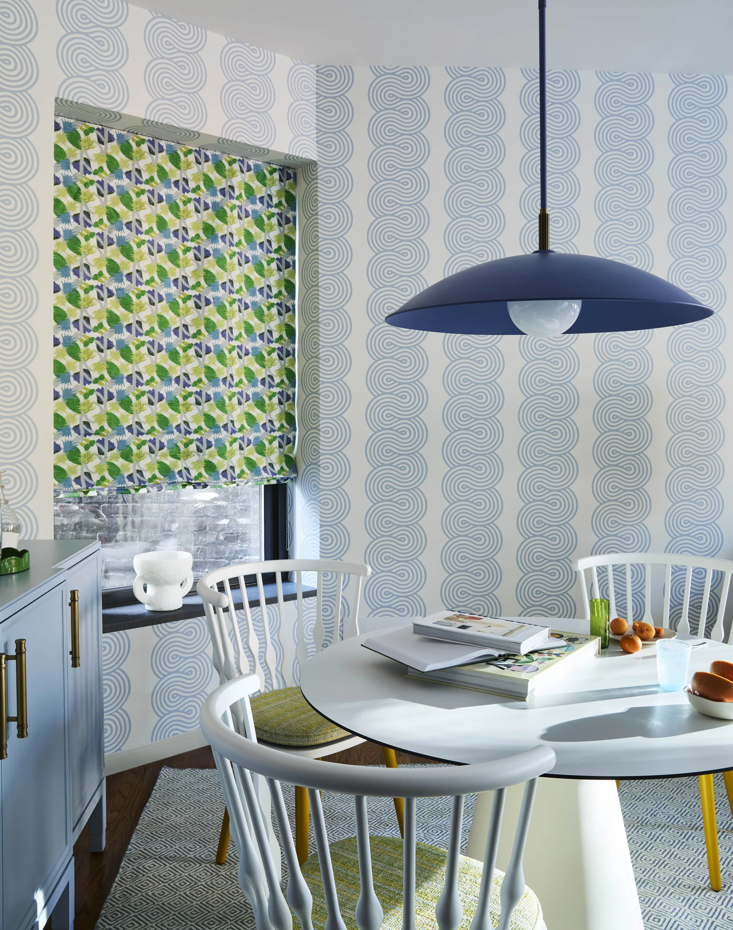 Custom wall covering in green print, blue print wallpaper and blue pendant in dining area. 