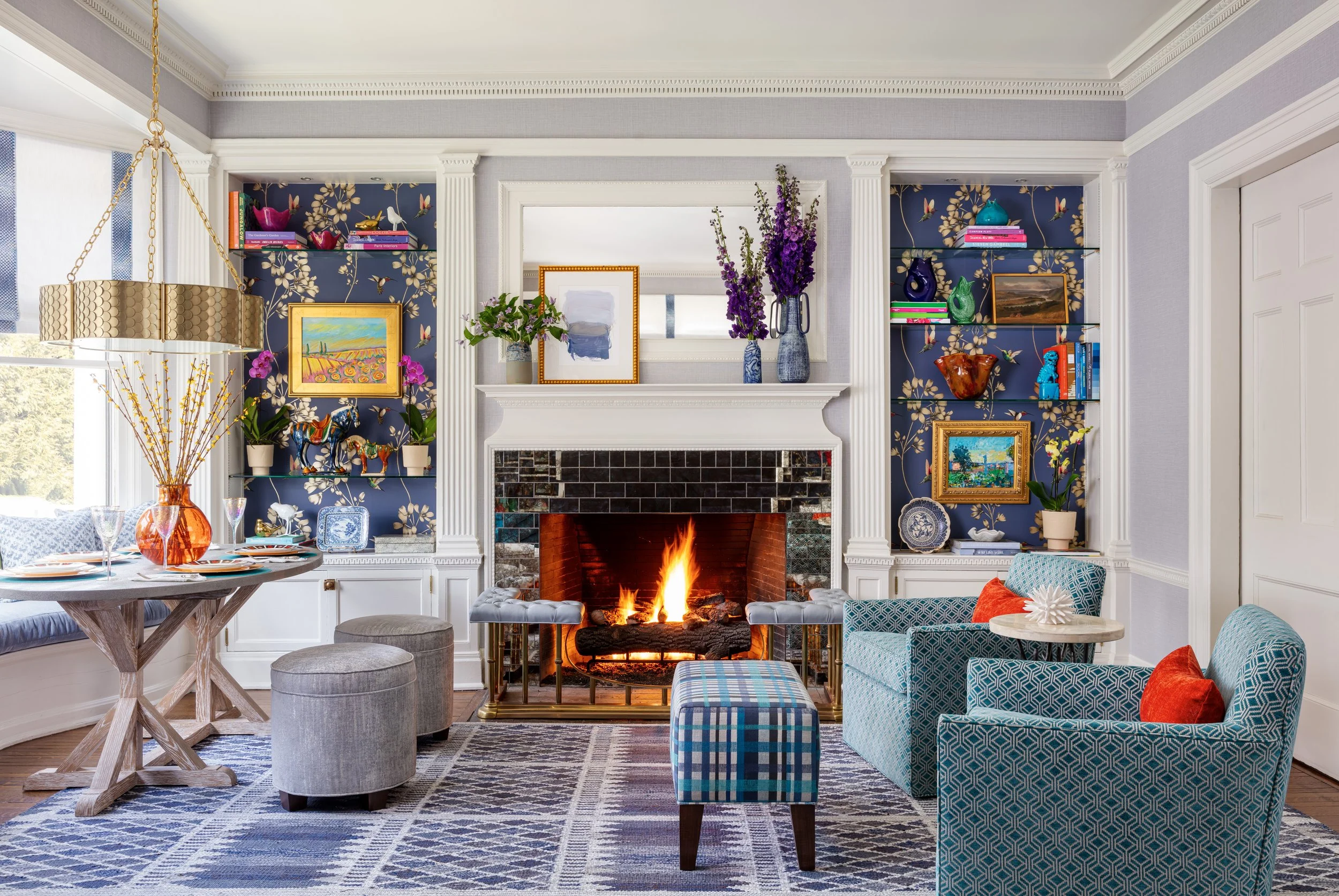 inviting living room with lounge chairs table fireplace and built in bookcase with wallpaper behind shelves 
