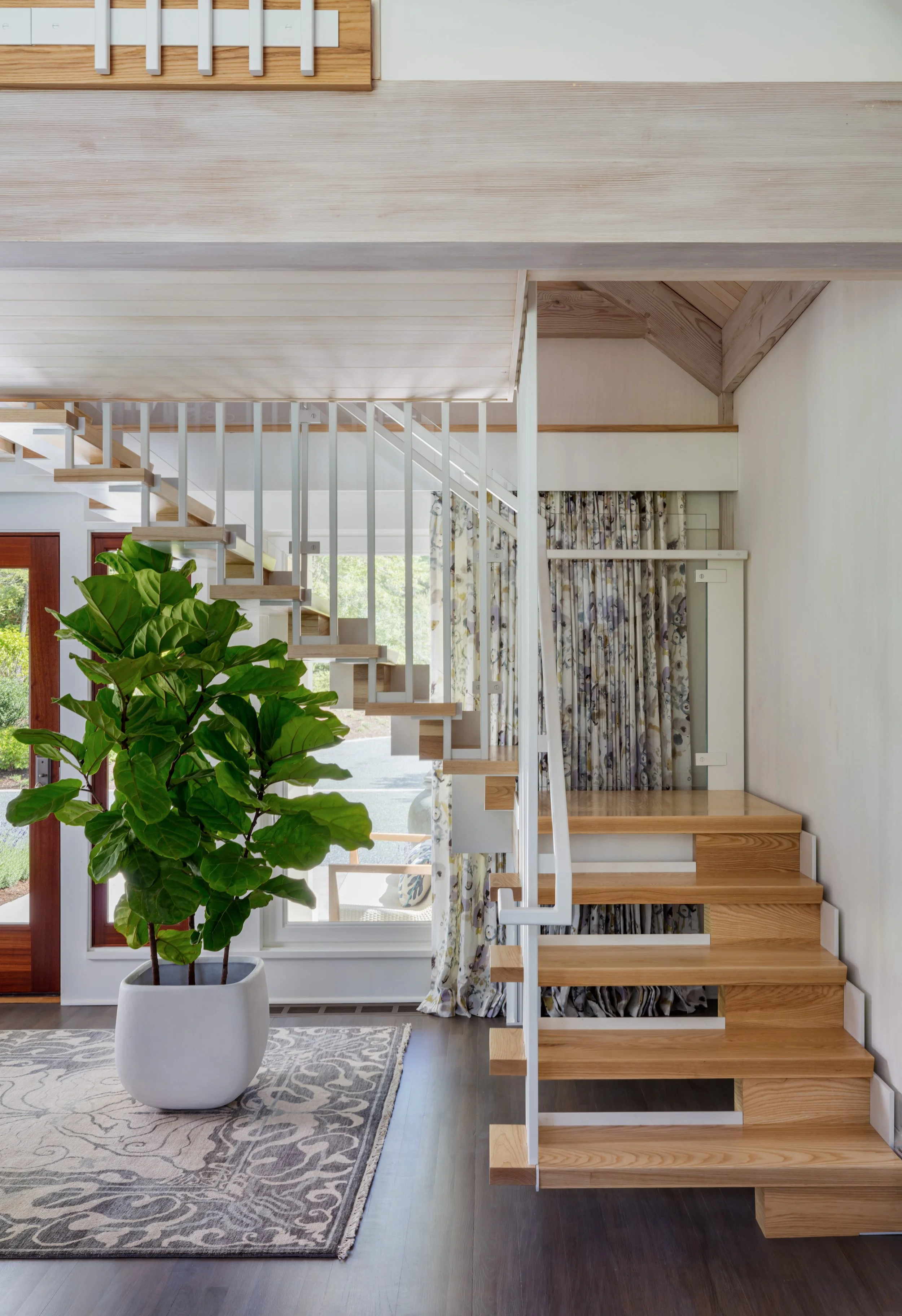 modern wooden staircase with white railings and patterned rug