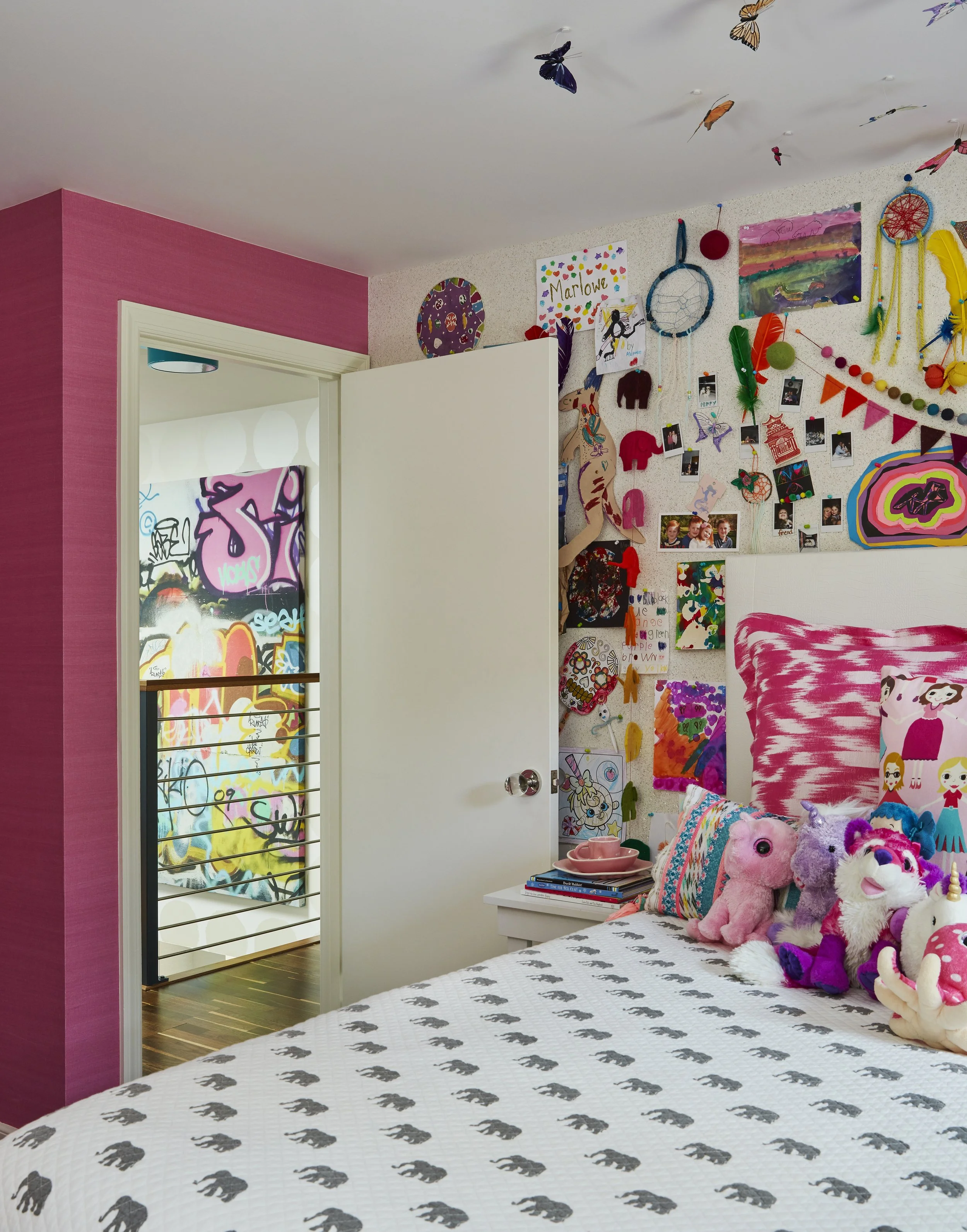 kids bedroom with art wall pink walls and colorful bedding