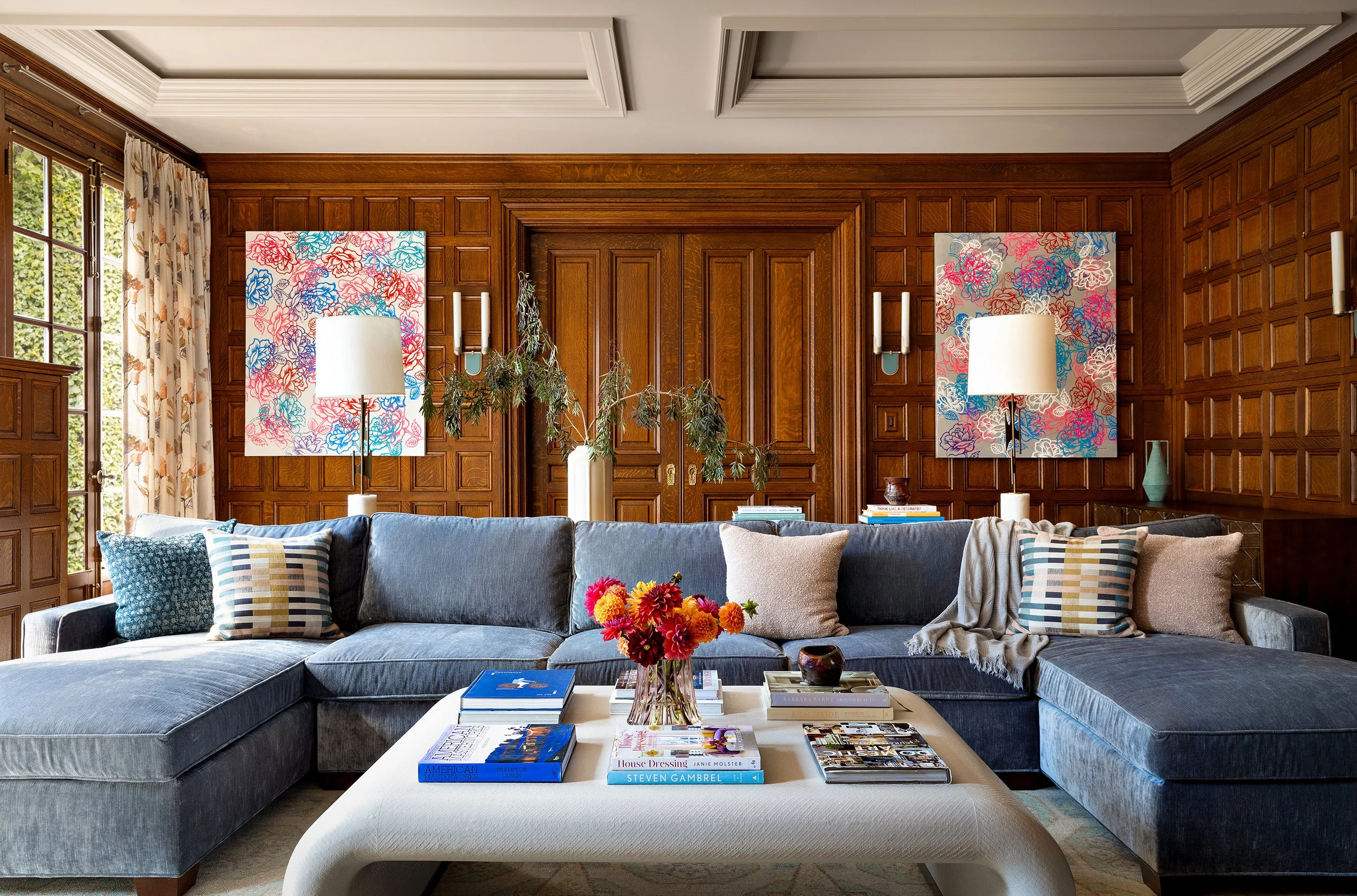 inviting family room with blue u shaped sectional and large ottoman bright artwork for wood panel walls