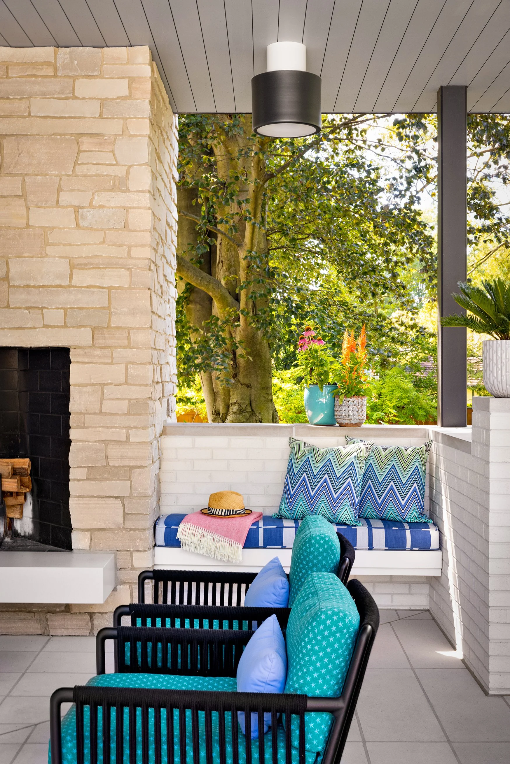 covered patio with built in bench seating beside stone fireplace for outdoor living