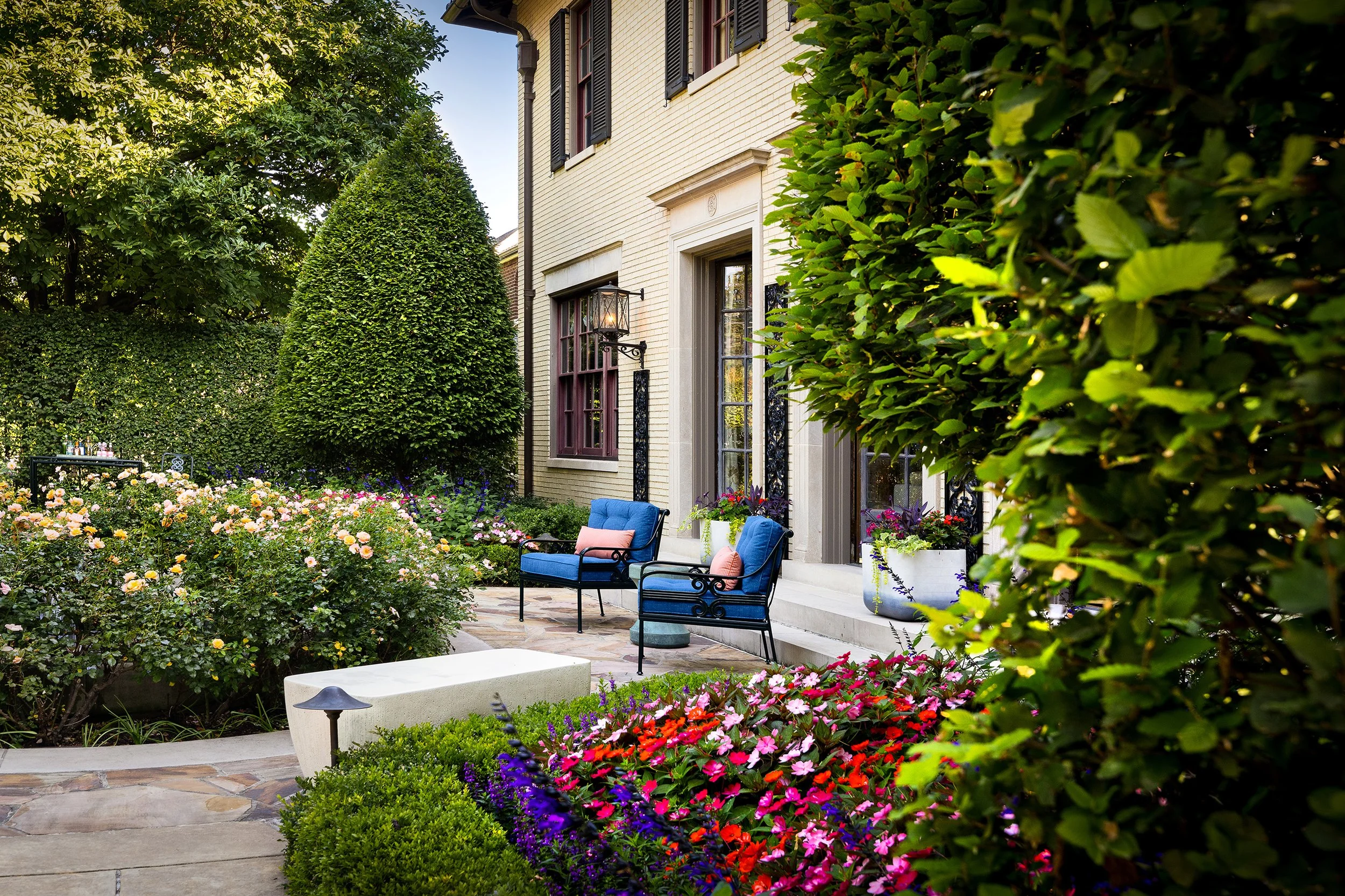 stately house exterior with flower garden and  blue lounge chairs