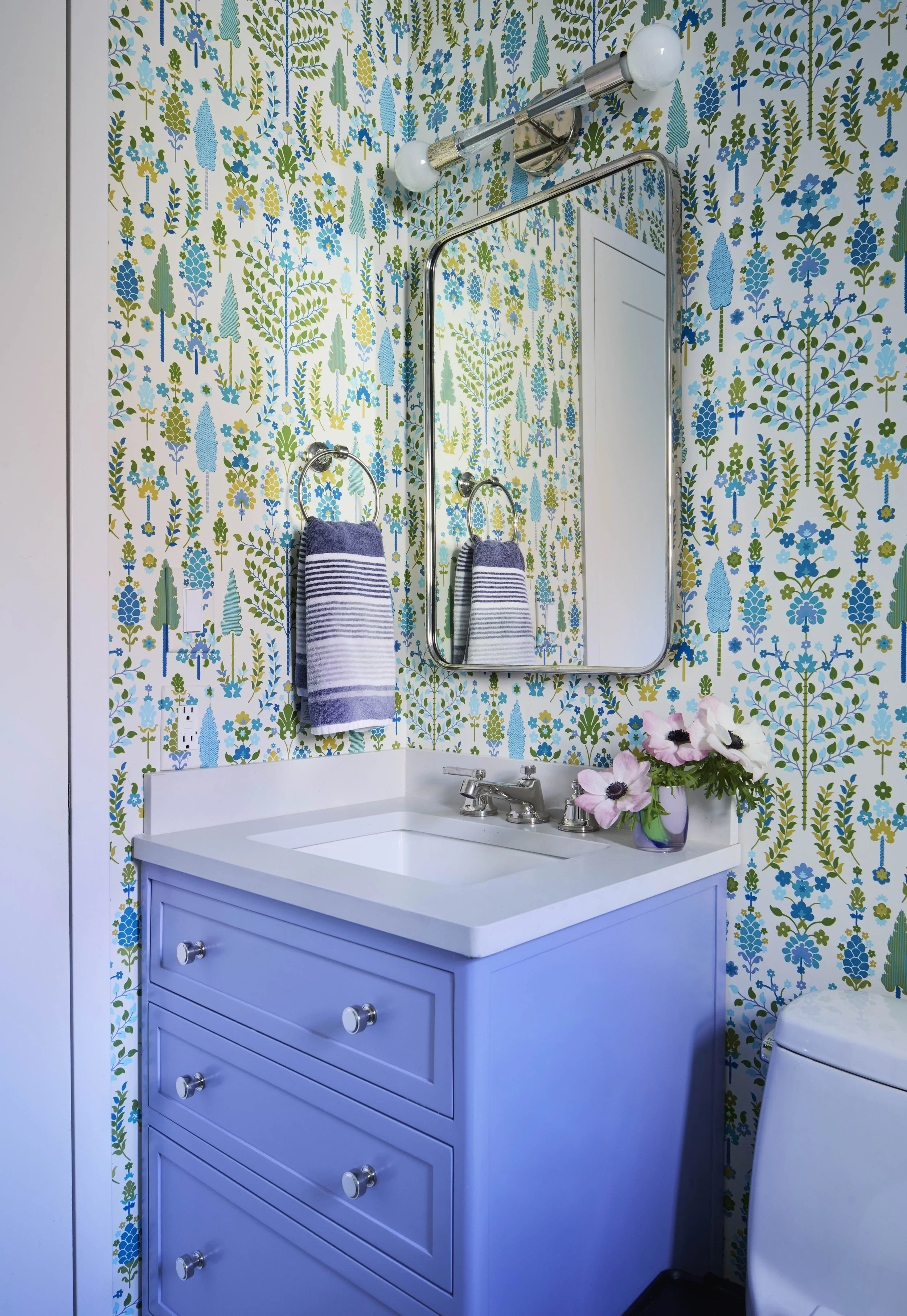 Wallpapered bathroom with painted vanity. 