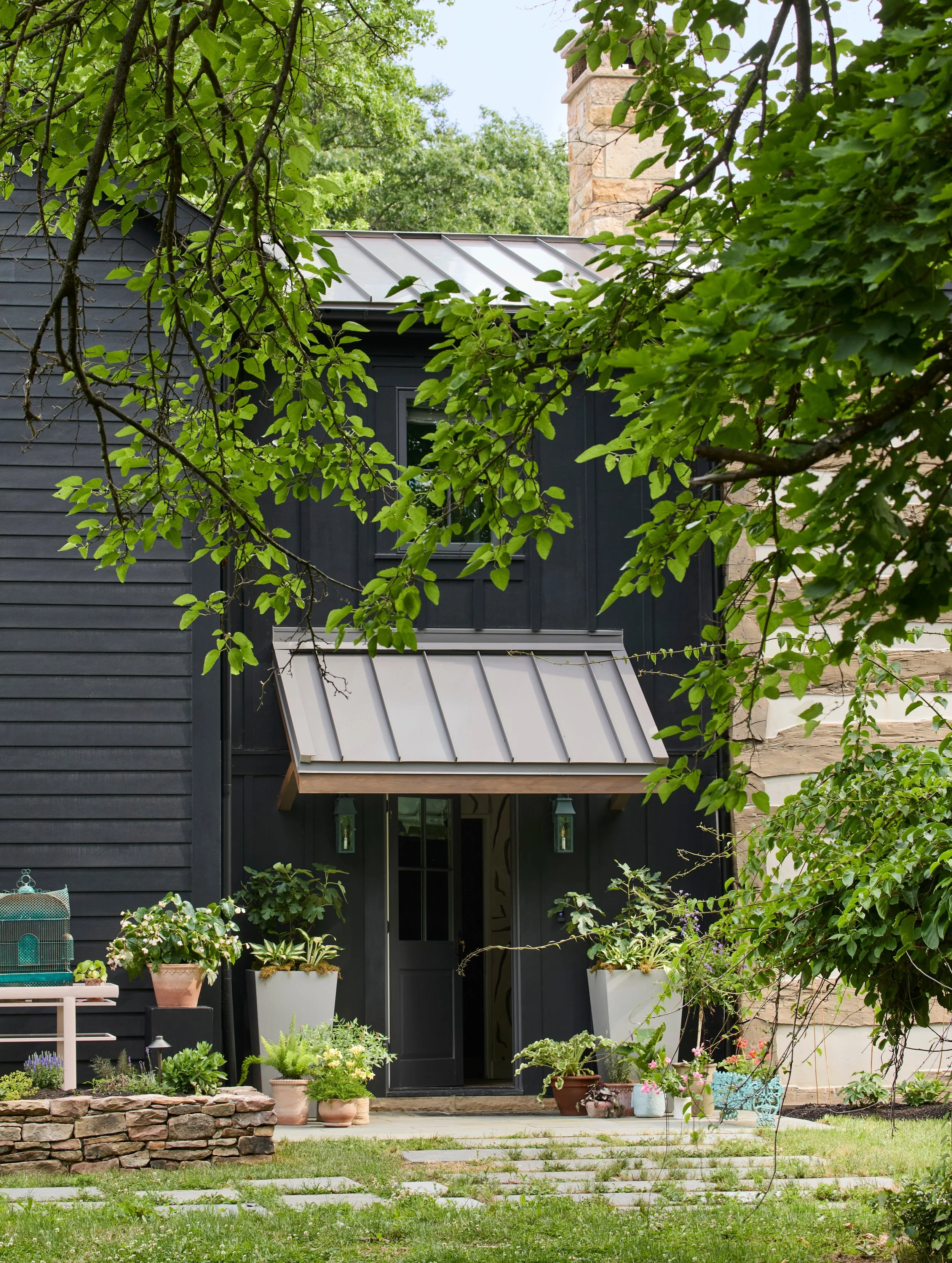 log-cabin-renovation-black-siding-metal-awning-entry-plants-04.jpg