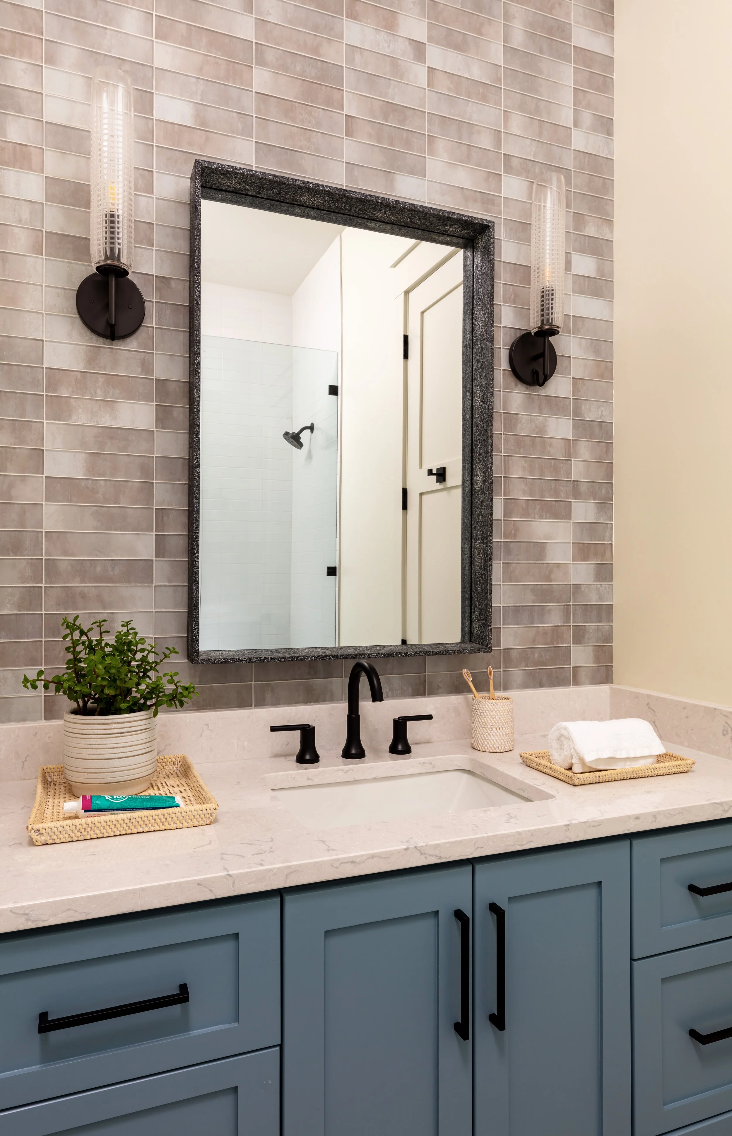 modern bathroom with blue vanity, sleek mirror, tiled backsplash, and sconces for bathroom design inspiration