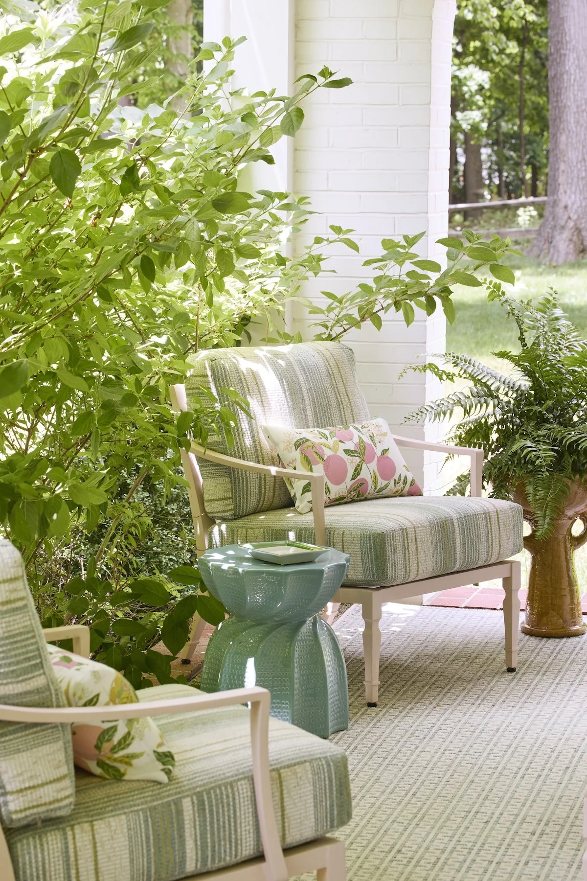 side porch seating with pastel striped armchairs aqua garden stools botanical pillows betsy wentz