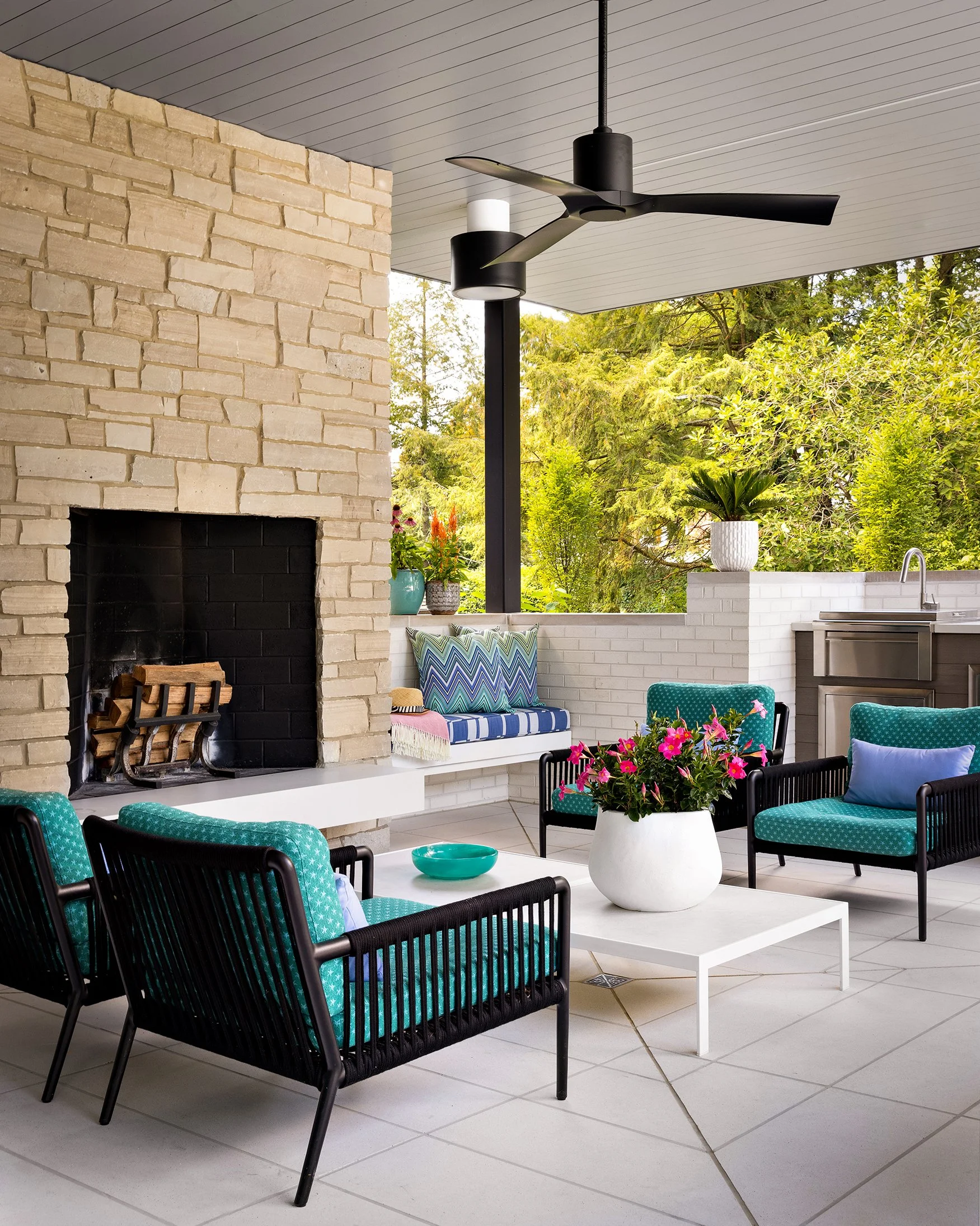 covered outdoor patio with lounge chairs coffee tables and built in seating by stone fireplace