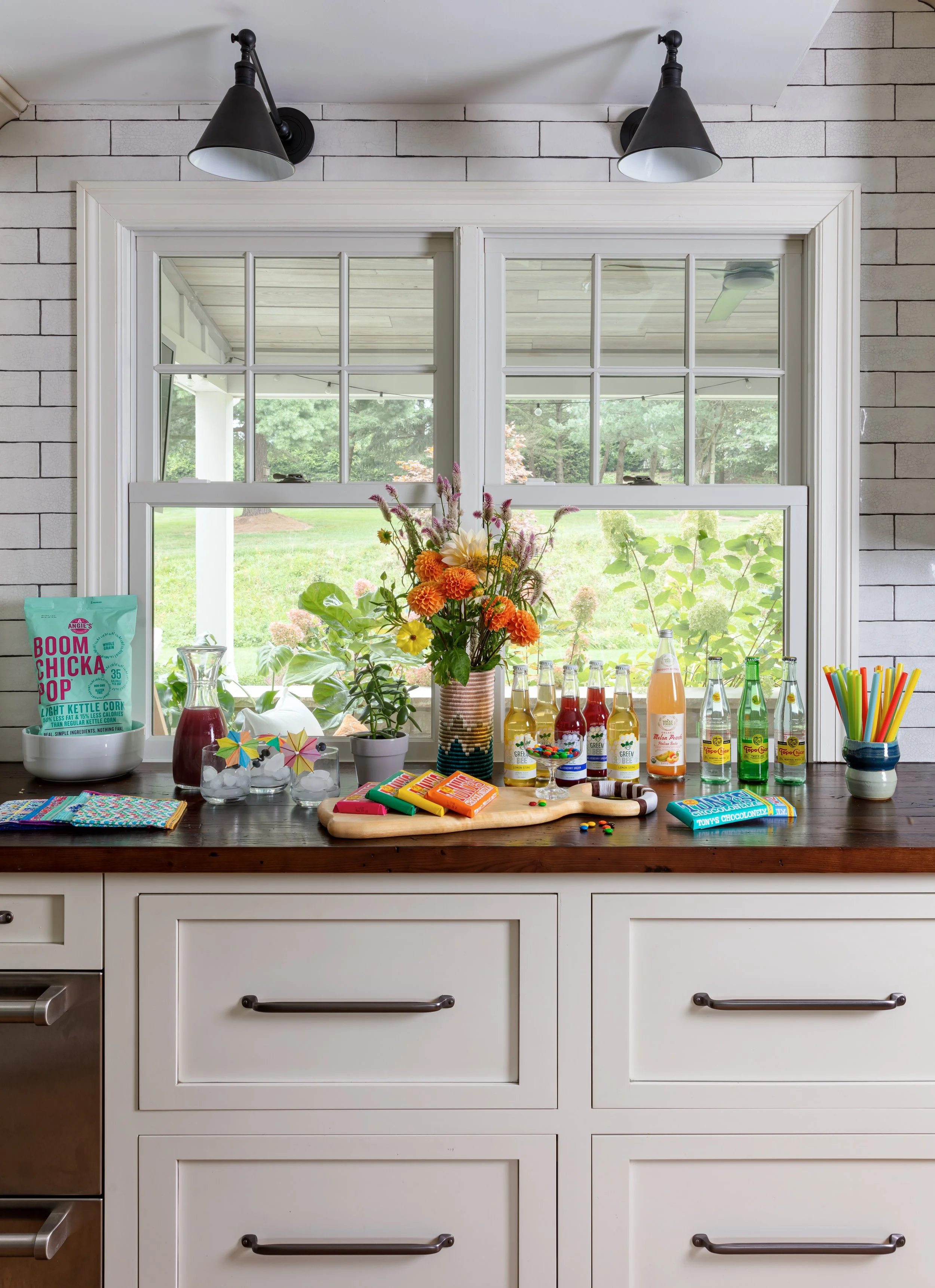 modern kitchen with white cabinetry, dark wood countertop, subway tile backsplash, and wall sconces for chic home entertaining design inspiration.