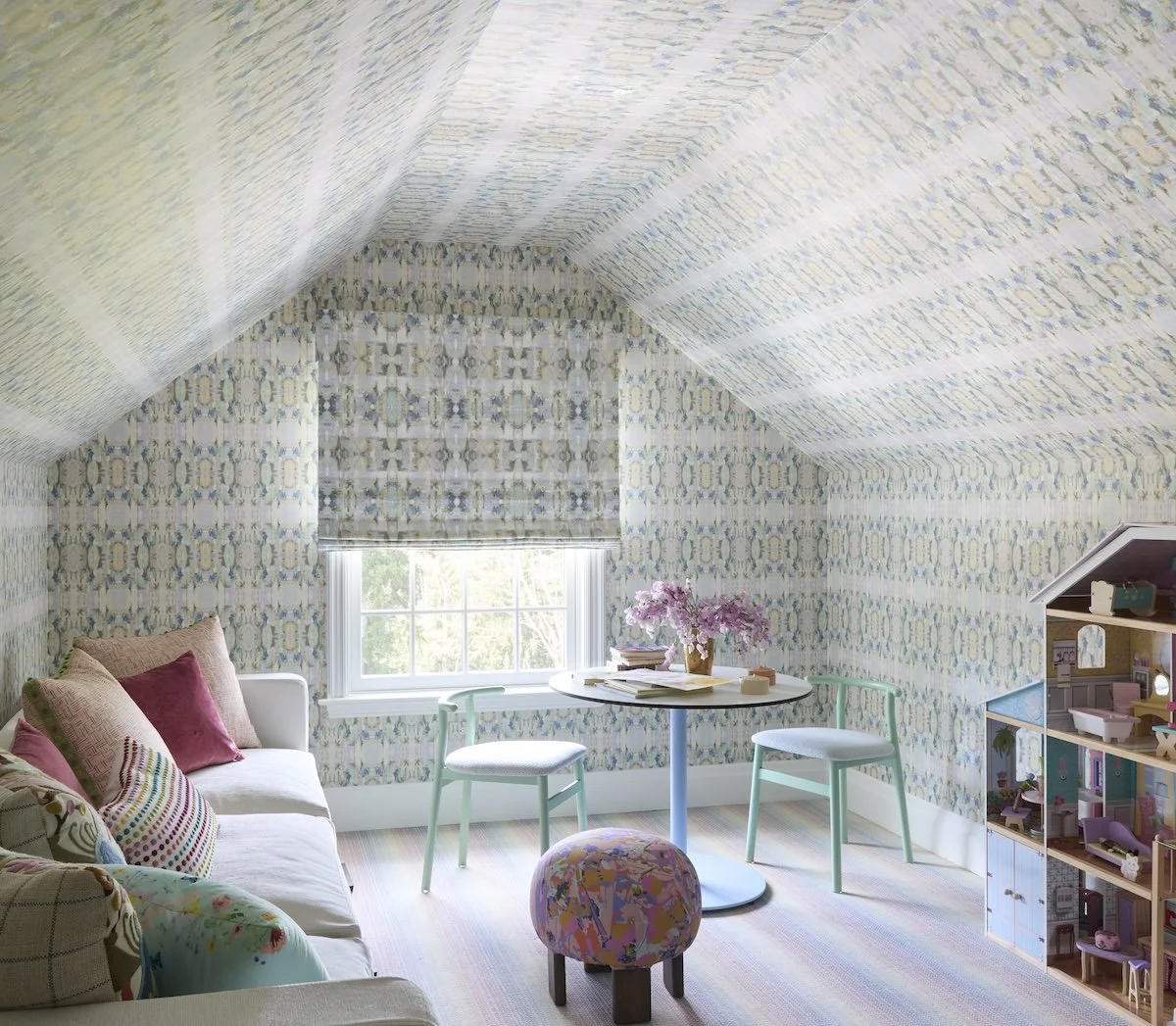 whimsical attic playroom with pastel patterned wallpaper vaulted ceiling white sofa small round table dollhouse by betsy wentz design