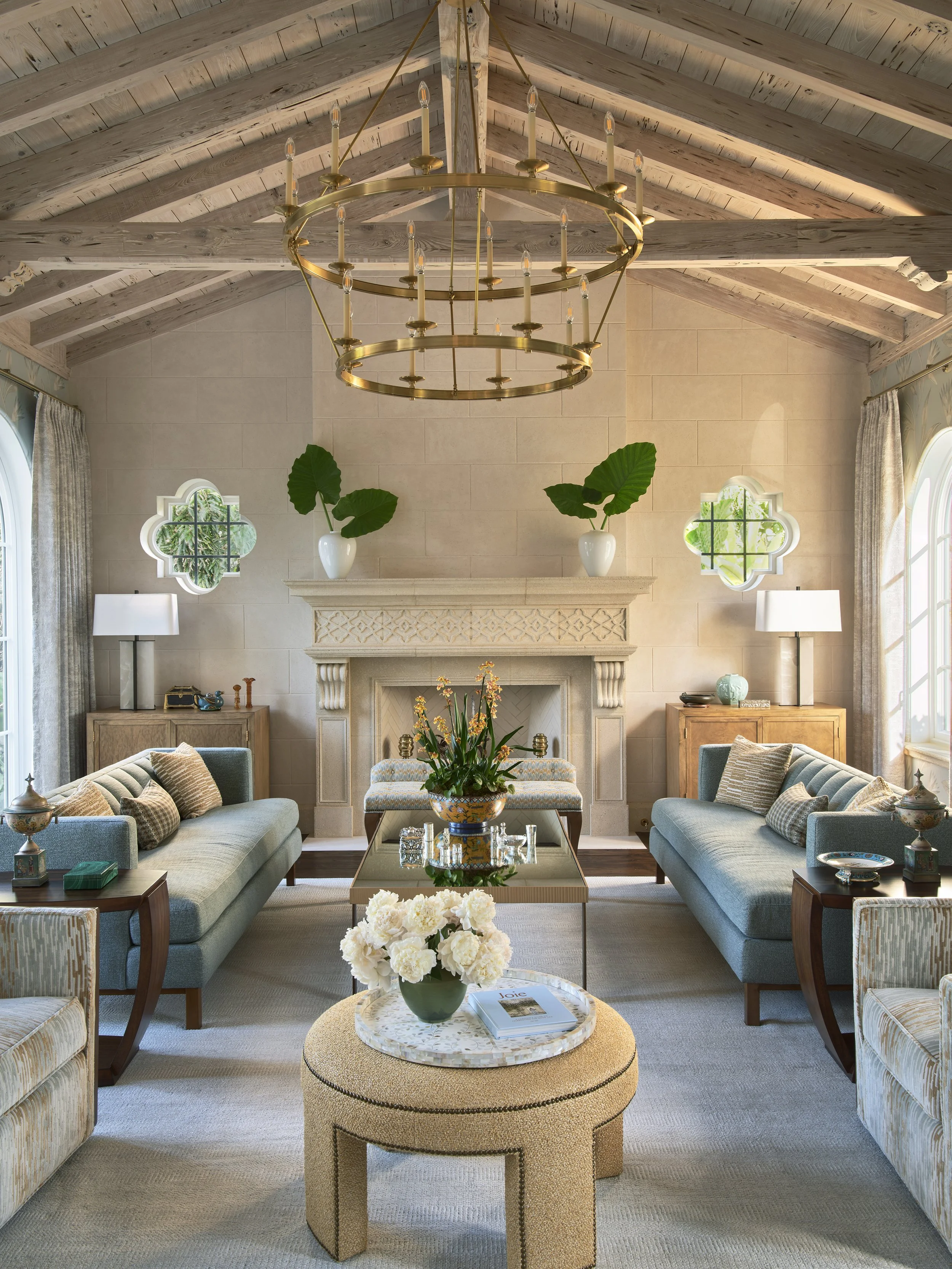 classic living room with vaulted ceiling exposed beams gold chandelier blue sofa fireplace