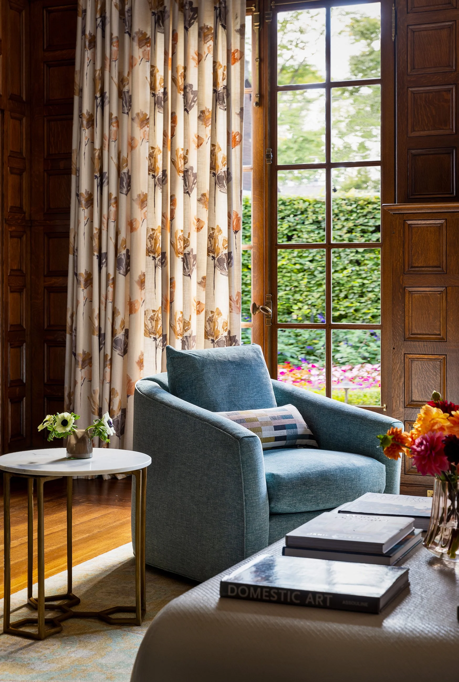 light filled family room cozy reading chair marble end table soft floral drapery