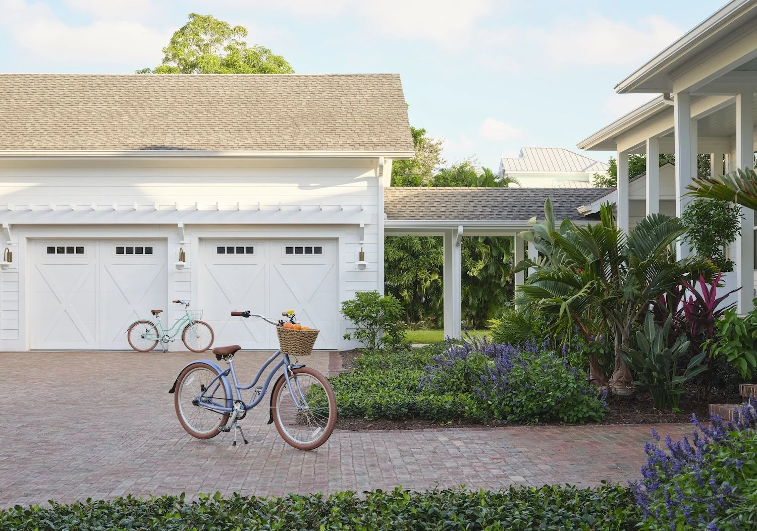 60-tropical-florida-home-exterior-white-garage-brick-driveway-bicycles-lush-landscaping-curb-appeal.jpg