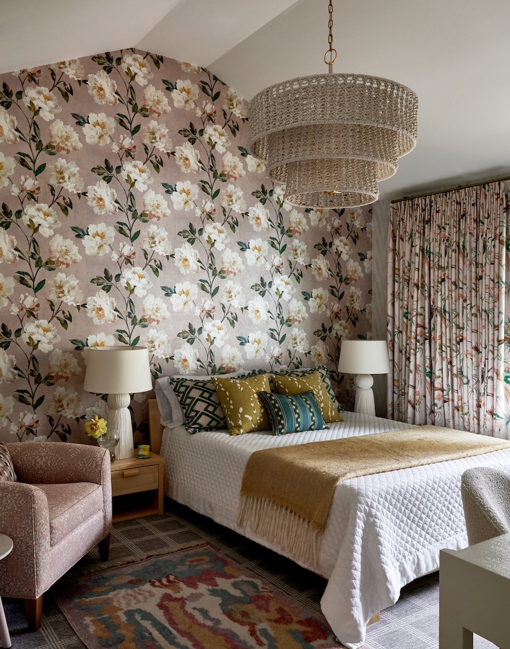 Blush bedroom floral wallpaper woven chandelier layered bedding patterned drapes 