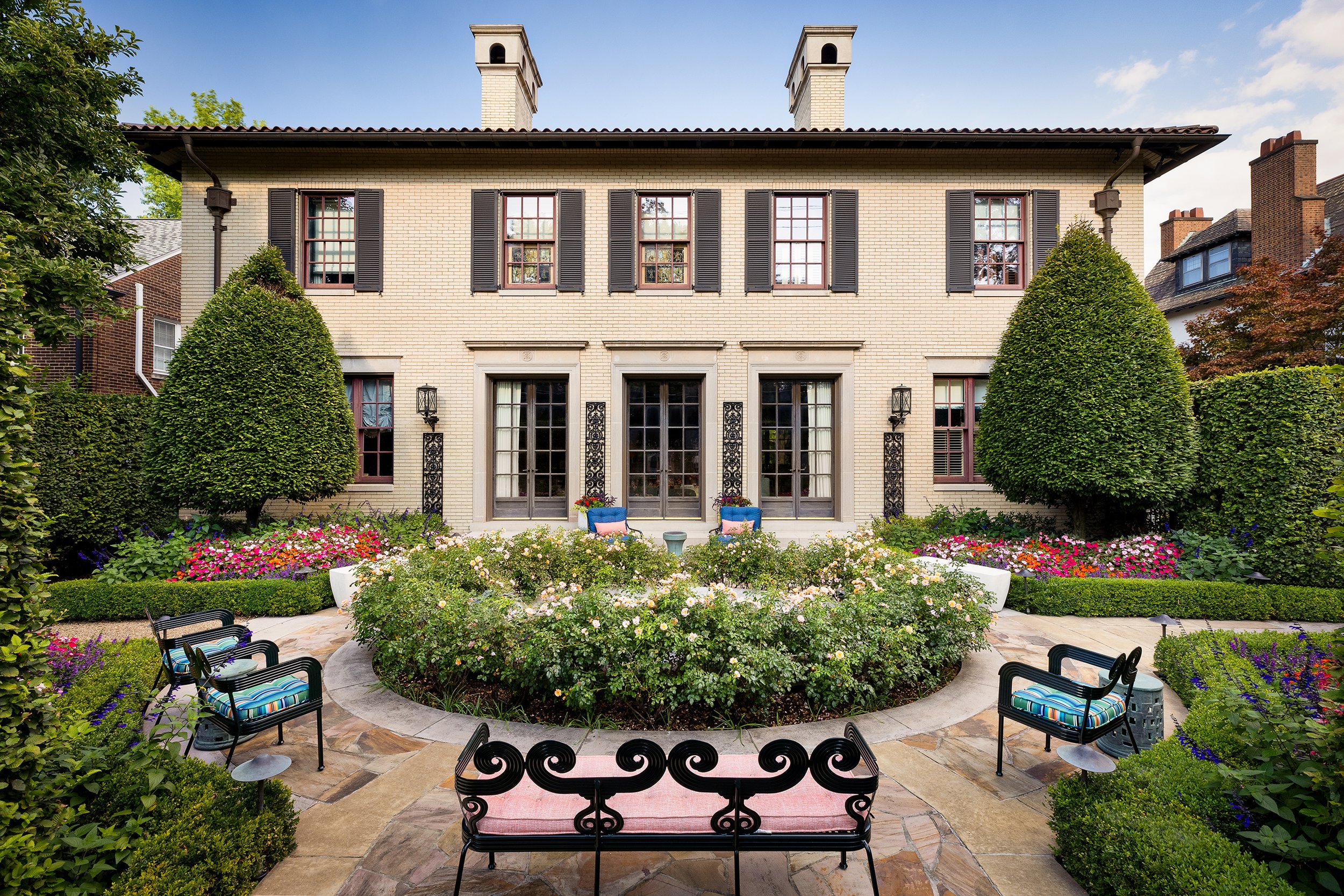 stately home with round rose garden entry and dark iton garden benches