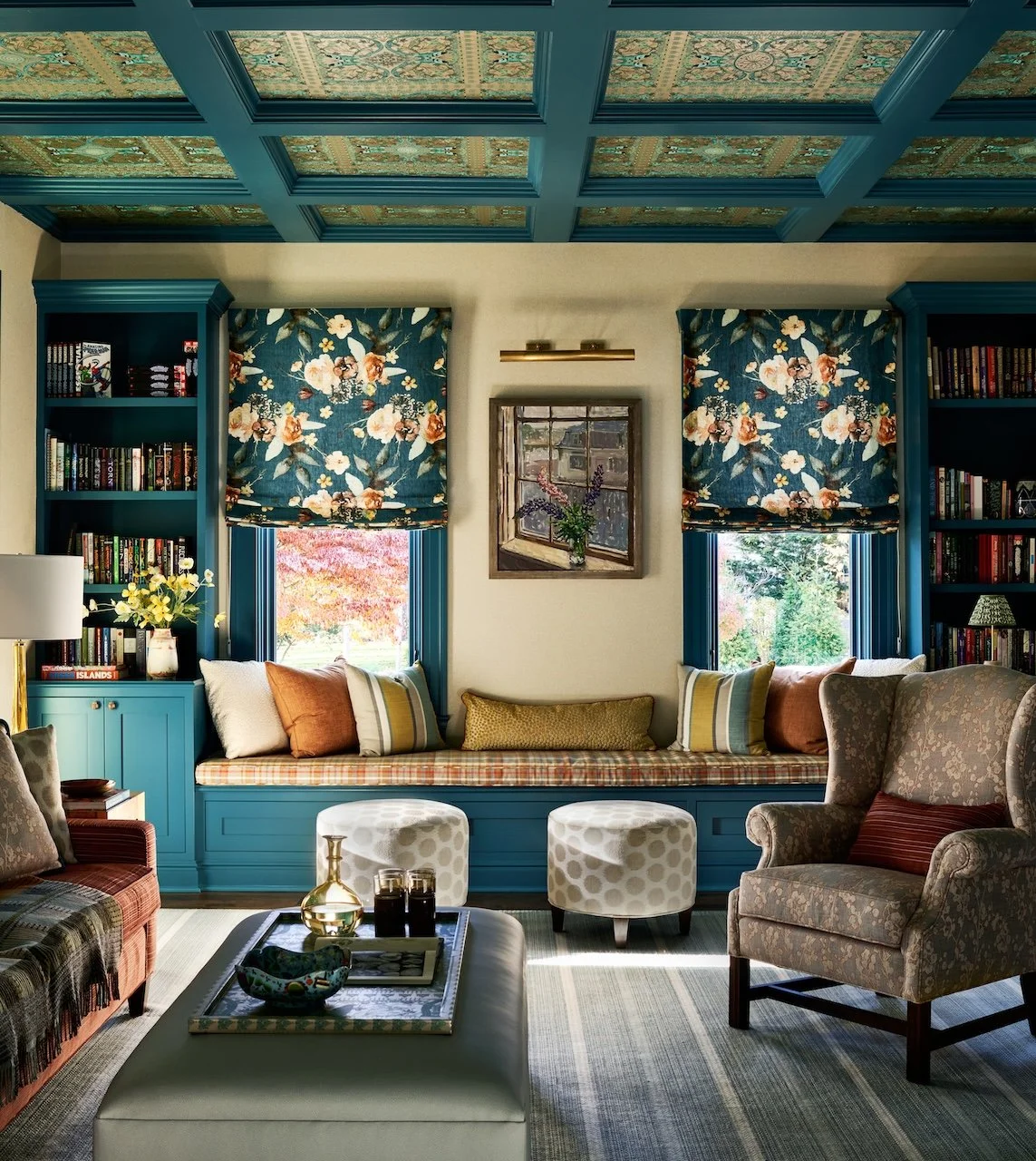Colorful library lounge teal built ins patterned coffered ceiling floral roman shades window seat