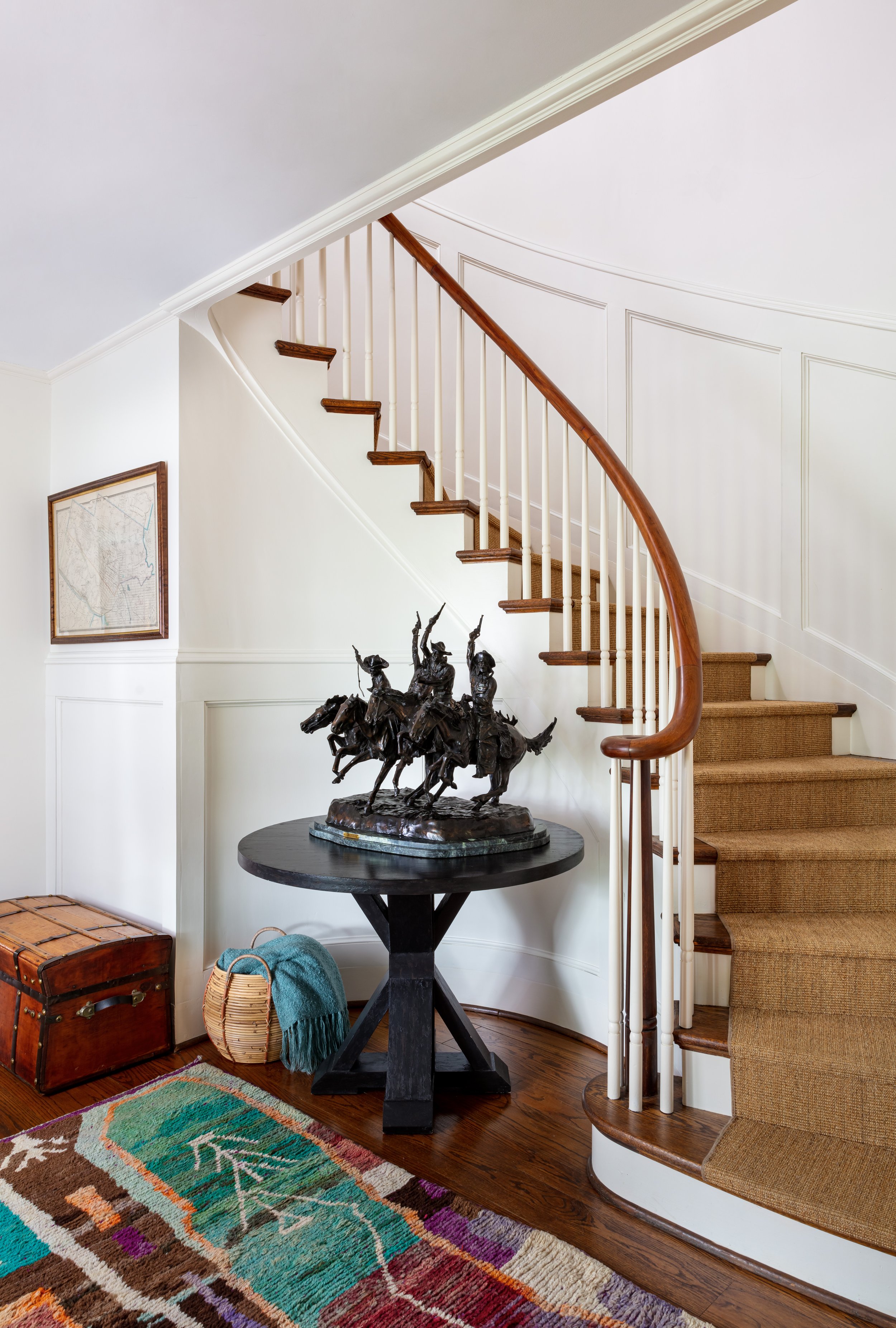 traditional entry with curved staircase and round table for art sculpture display