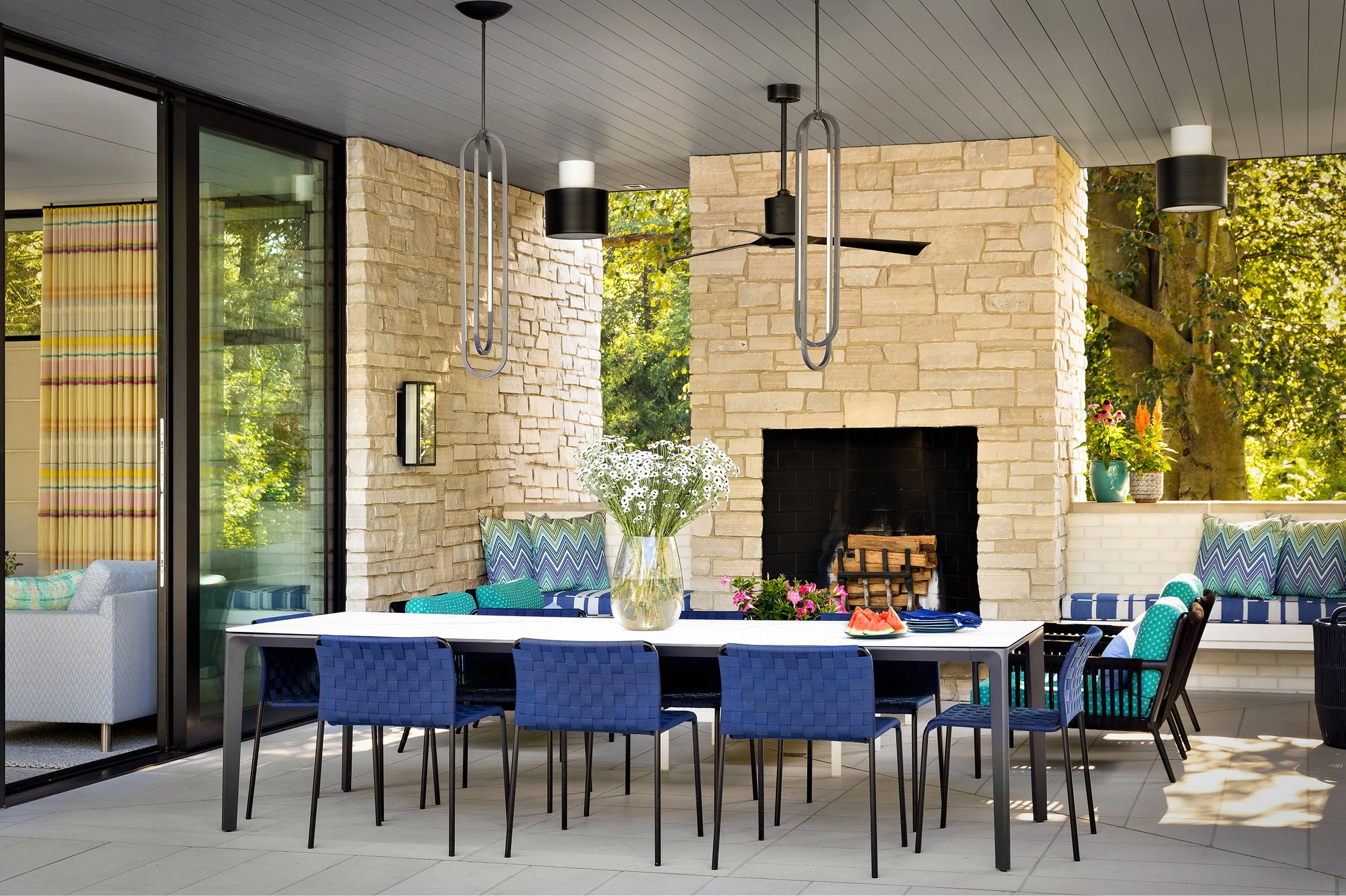covered outdoor patio for alfresco dining table and chairs stone fireplace with statement pendant lighting