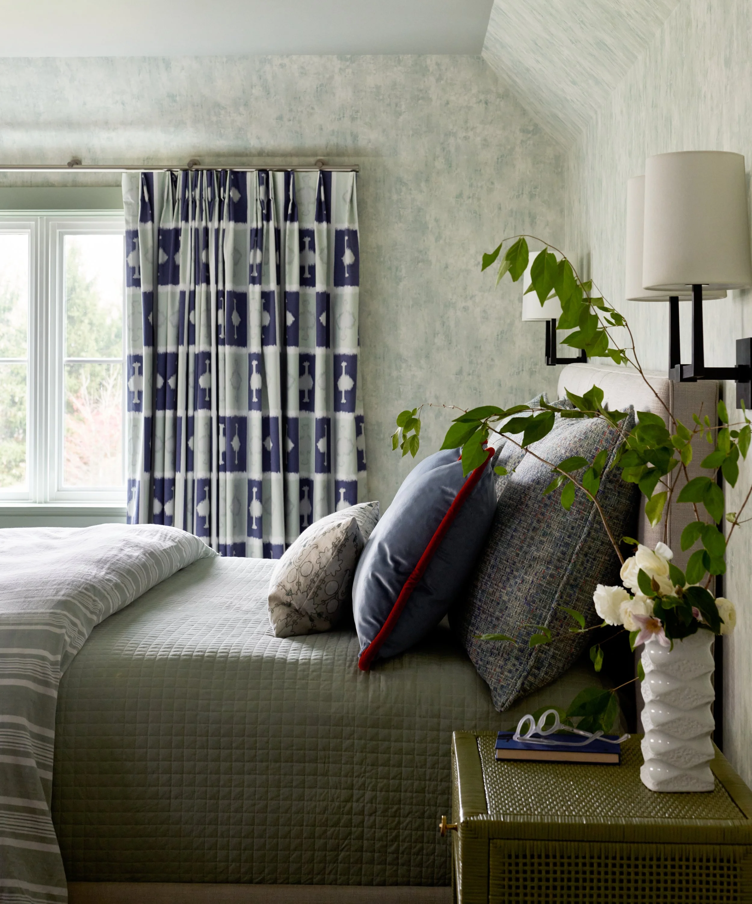 Guest bedroom with custom drapery, wallpaper on walls, and beautiful layered styling. 