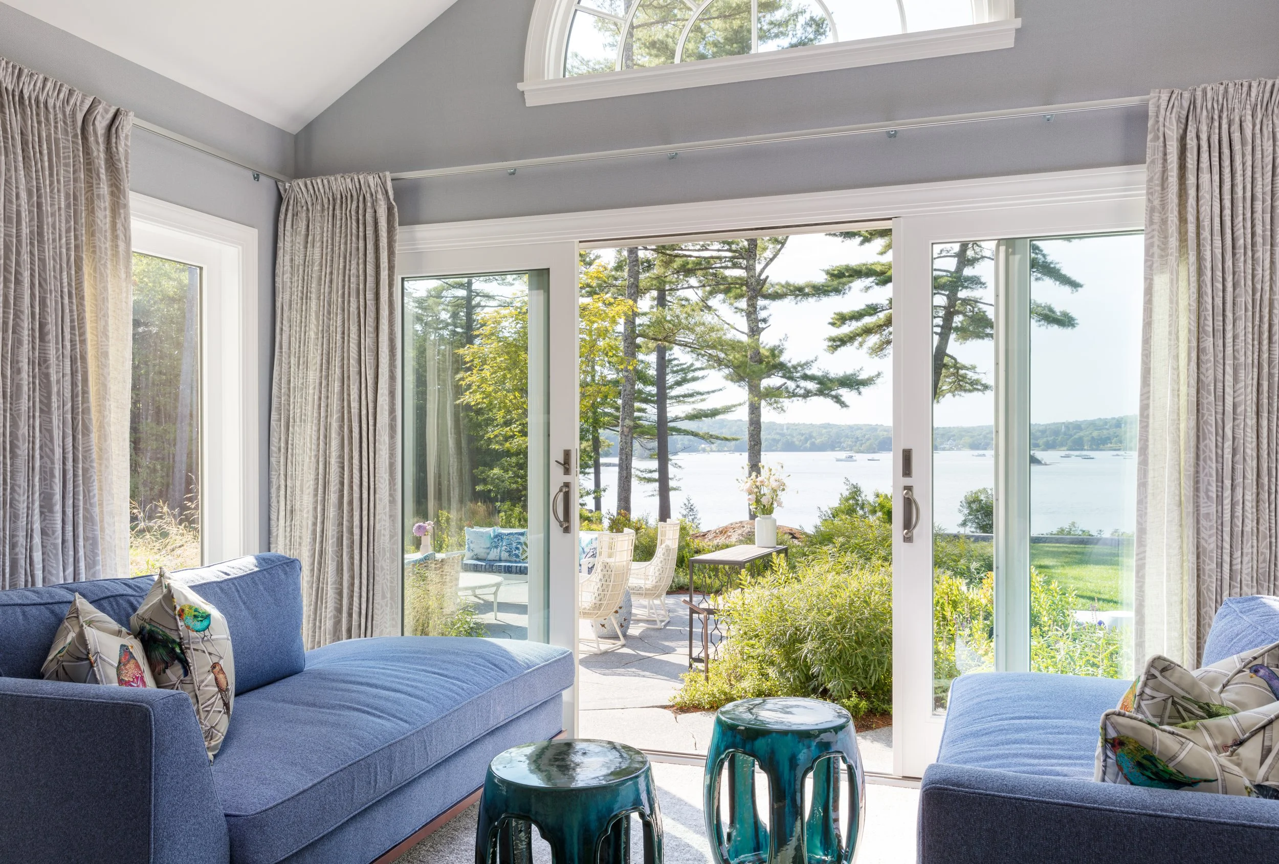 cozy living room with blue sofas, teal accent stools and french doors opening to patio  water view for relaxing retreat