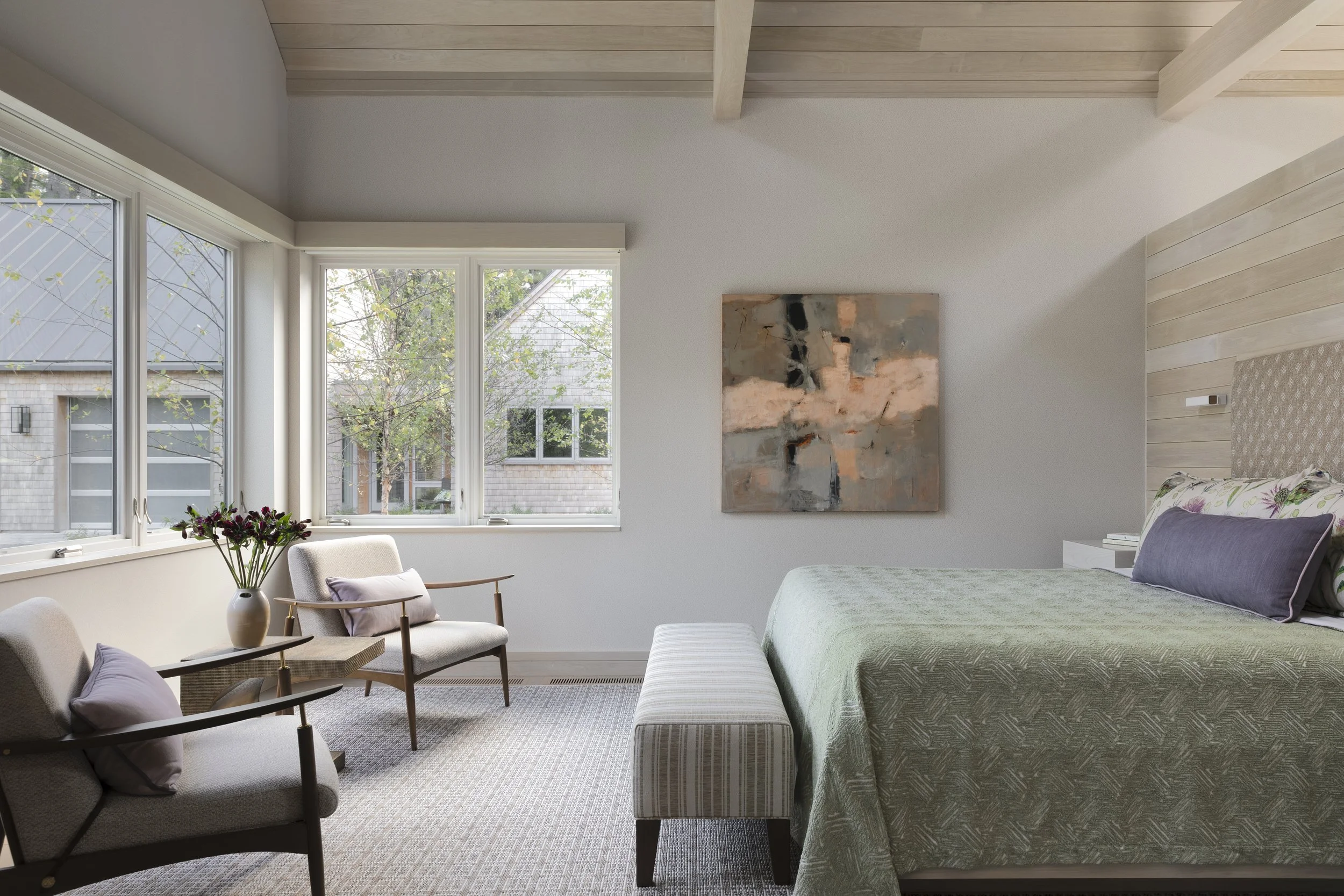 bedroom design with king bed, bench and reading chairs in soft green colors