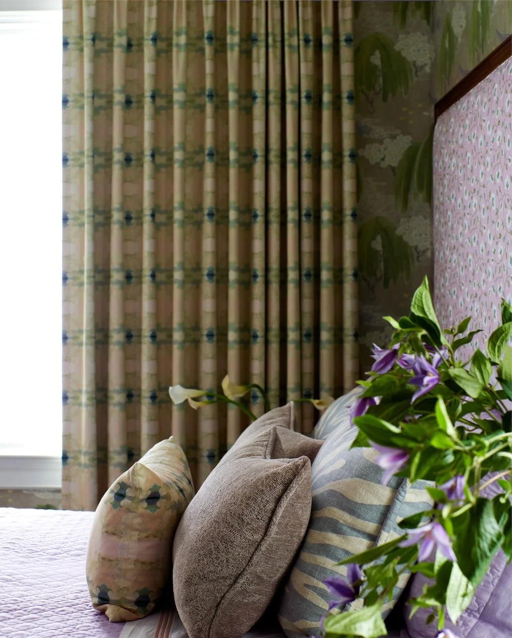Lilac upholstered bed patterned drapes layered pillows 