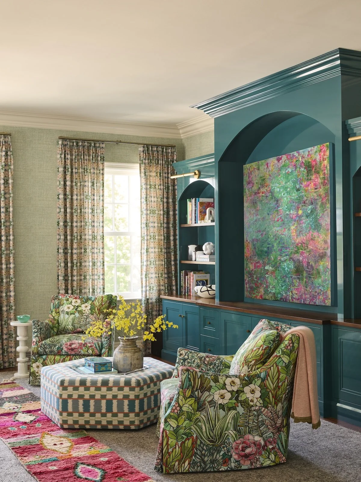 Colorful family library with teal lacquered built-ins, botanical floral swivel chairs, patterned curtains and oversized abstract art by Betsy Wentz