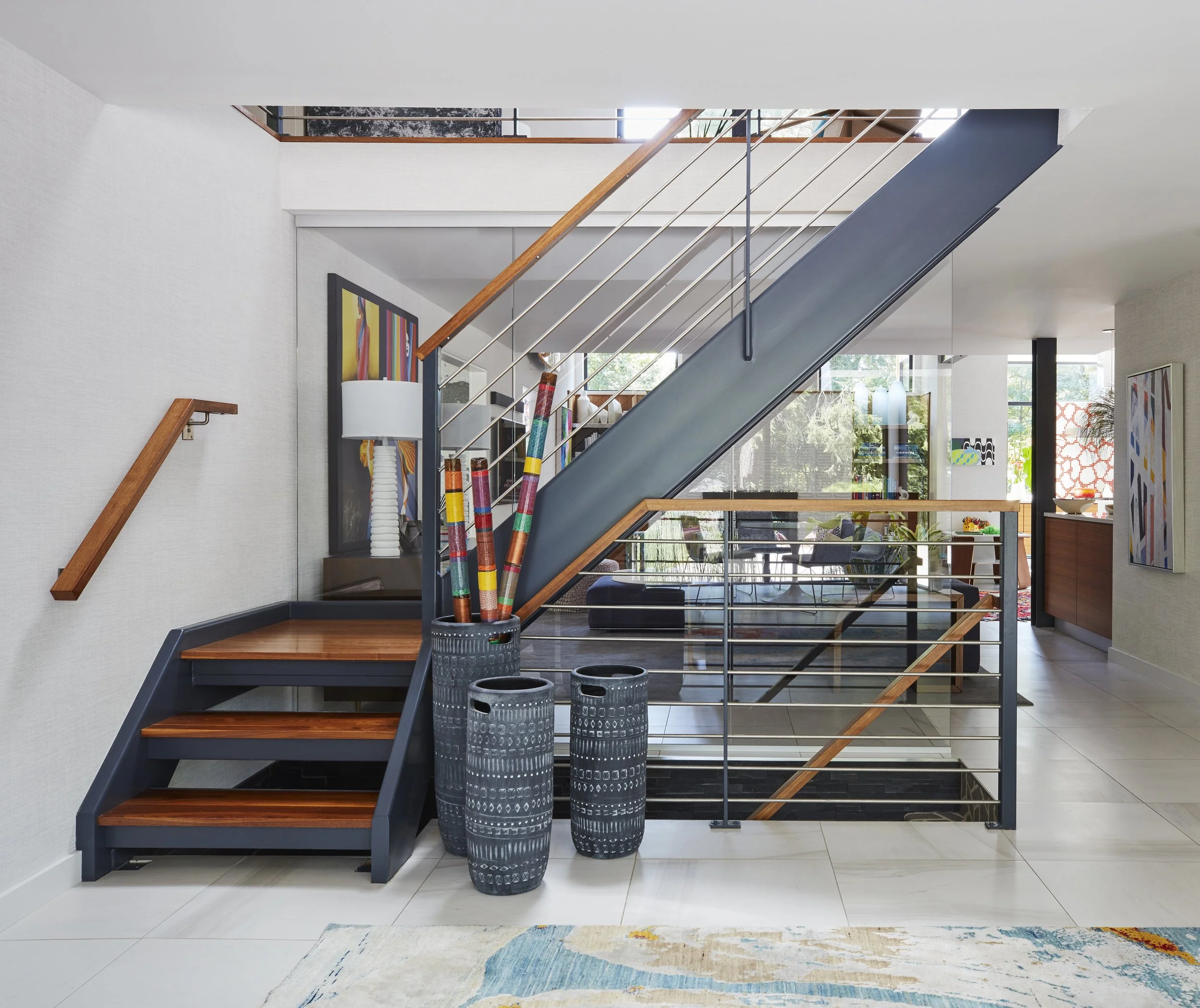 modern open concept staircase with wooden steps dark stringer metal balusters colorful art decor enhancing entryway design