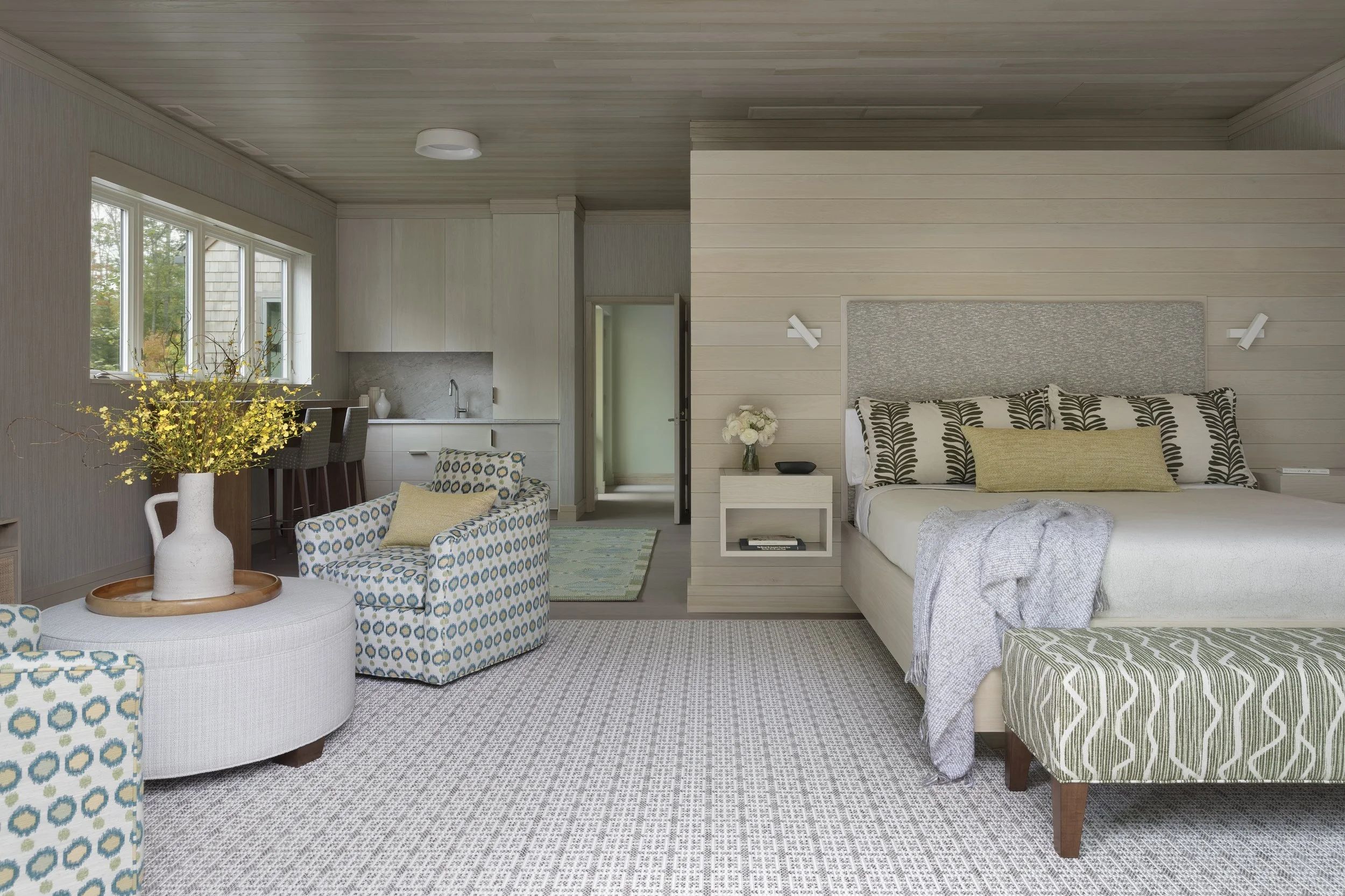 modern bedroom with king bed bench and lounge chairs with ottoman for conversation area 