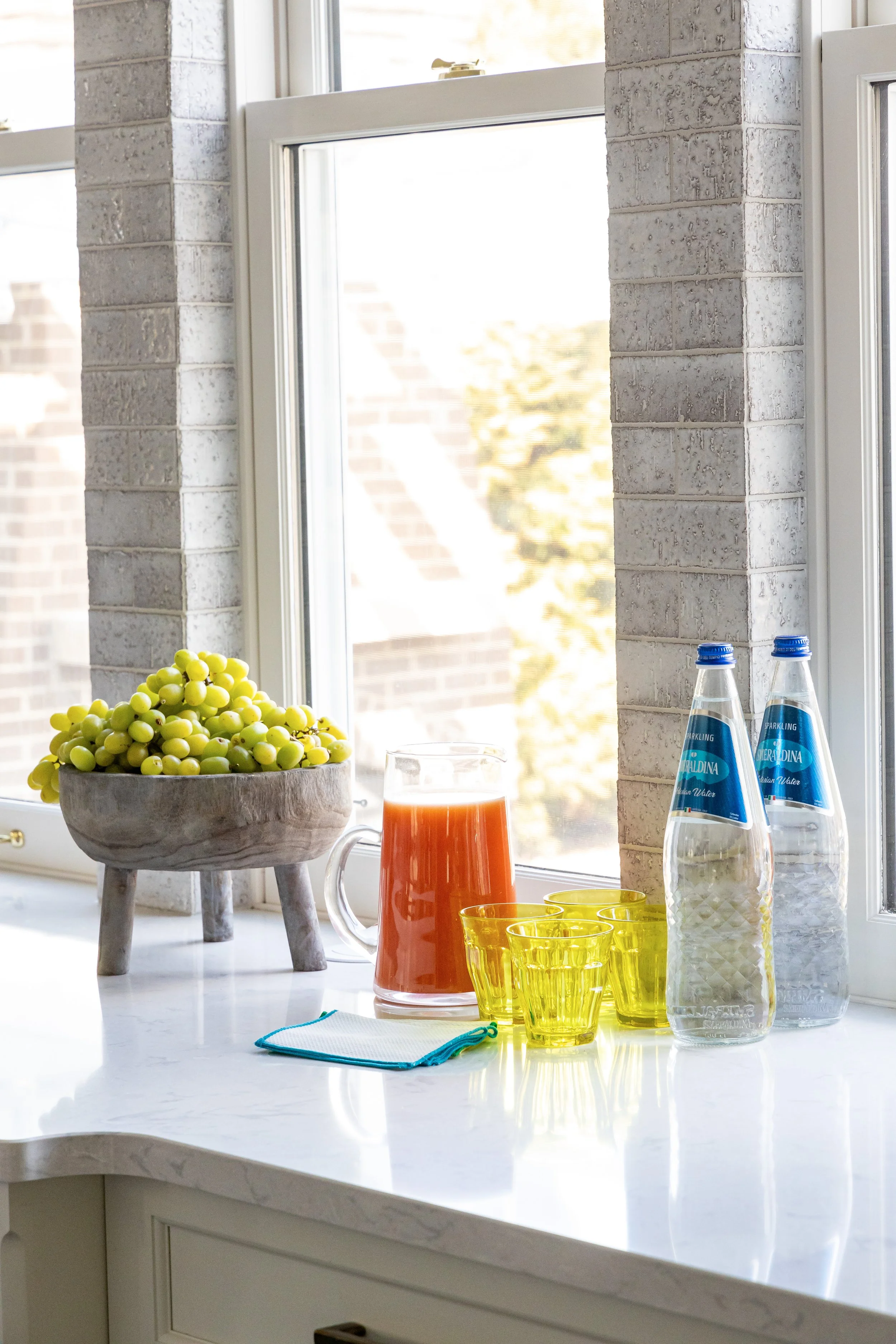 kitchen textured grey tile backsplash around windows and white quartz counter top 