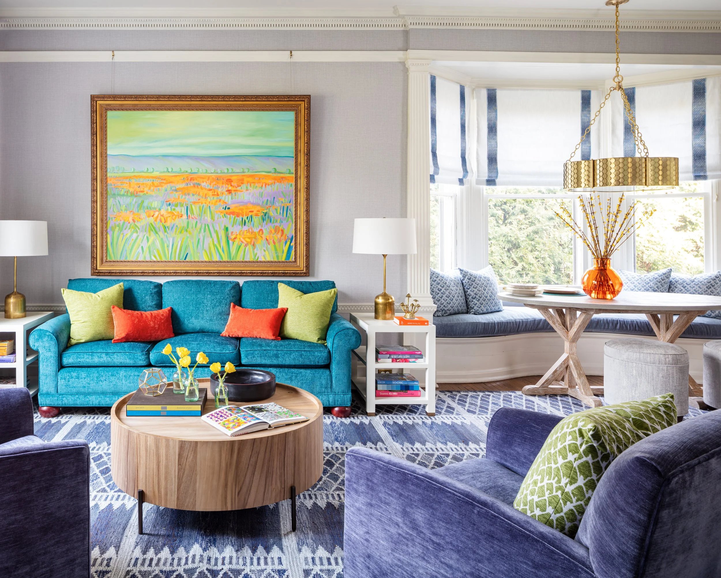 colorful living room with teal sofa bright pillows lounge chairs and round coffee table
