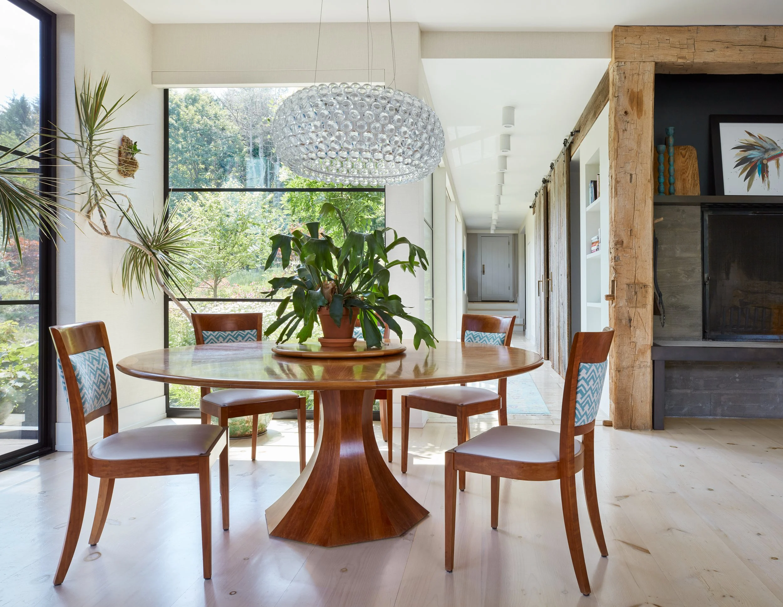 mid-century-modern-dining-room-design-featuring-a-round-wooden-table-with-pedestal-base-and-four-matching-chairs-adorned-with-blue-patterned-cushions-stylish-crystal-chandelier-adding-luxury-above-the-table-lush-green-plant-as-centerpiece-enhancing-natura.jpg