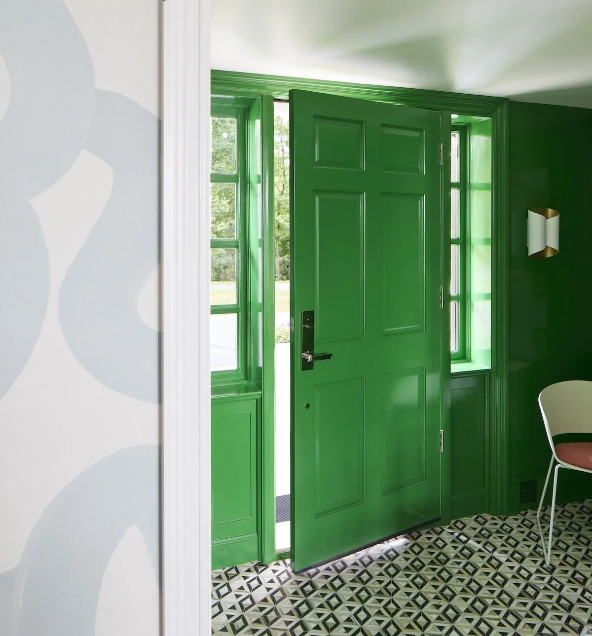 Bold emerald lacquered entry door with sidelights and graphic tiled floor. Vibrant high gloss green foyer interior design by Betsy Wentz