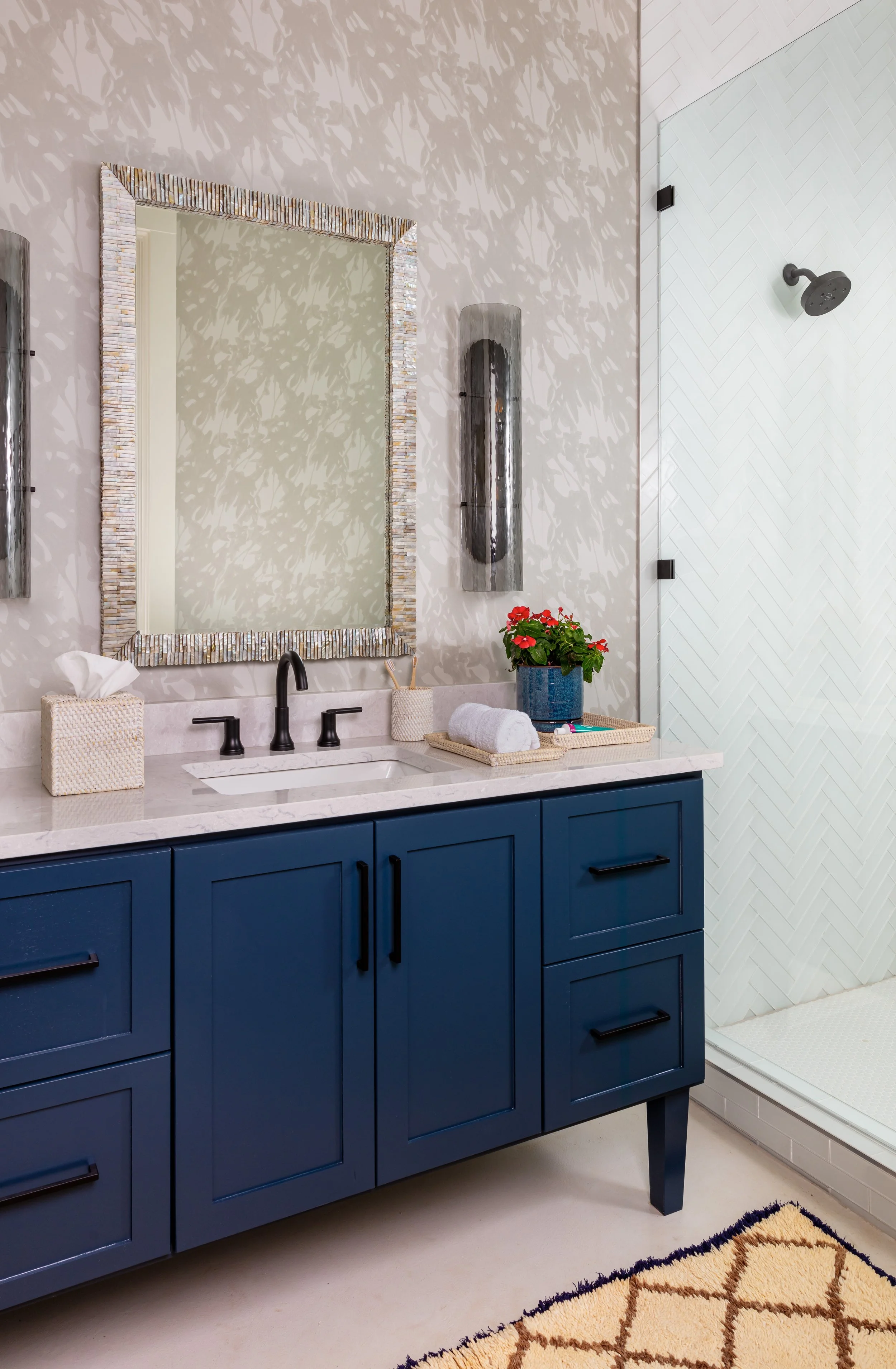 modern bathroom with blue vanity, silver mirror, marble wallpaper, and chic wall sconces for sleek home design inspiration
