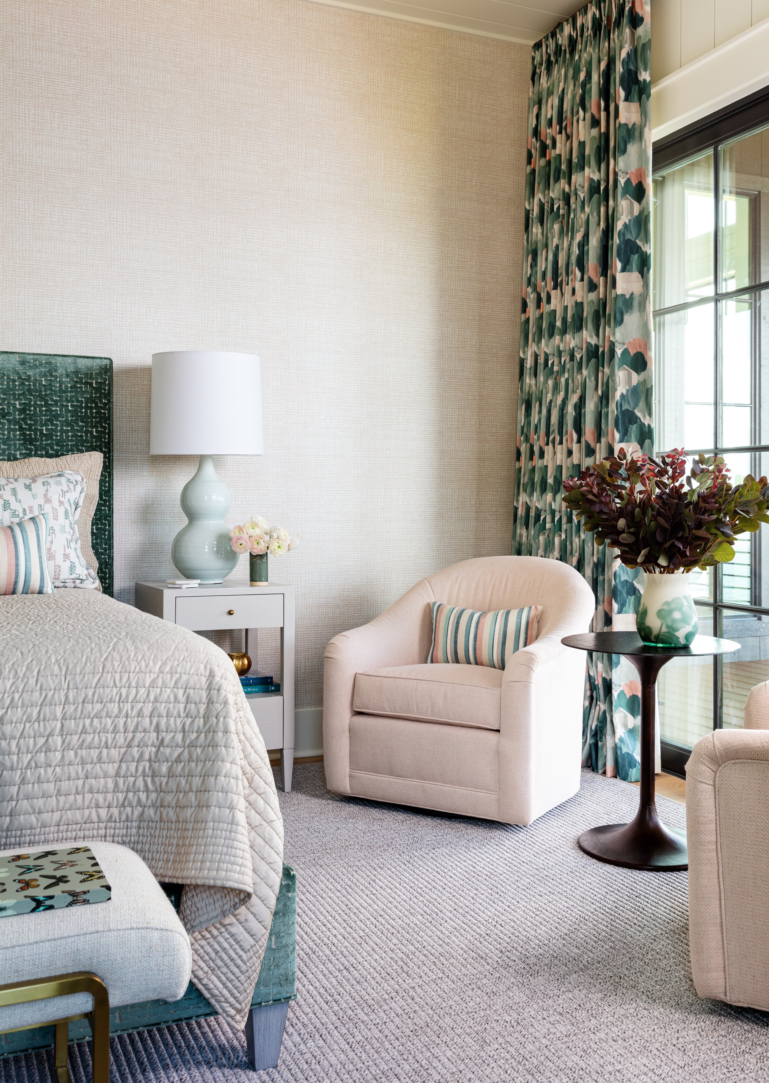 Coastal-inspired bedroom with two chairs for cozy reading corner, patterned curtains and beige bedding