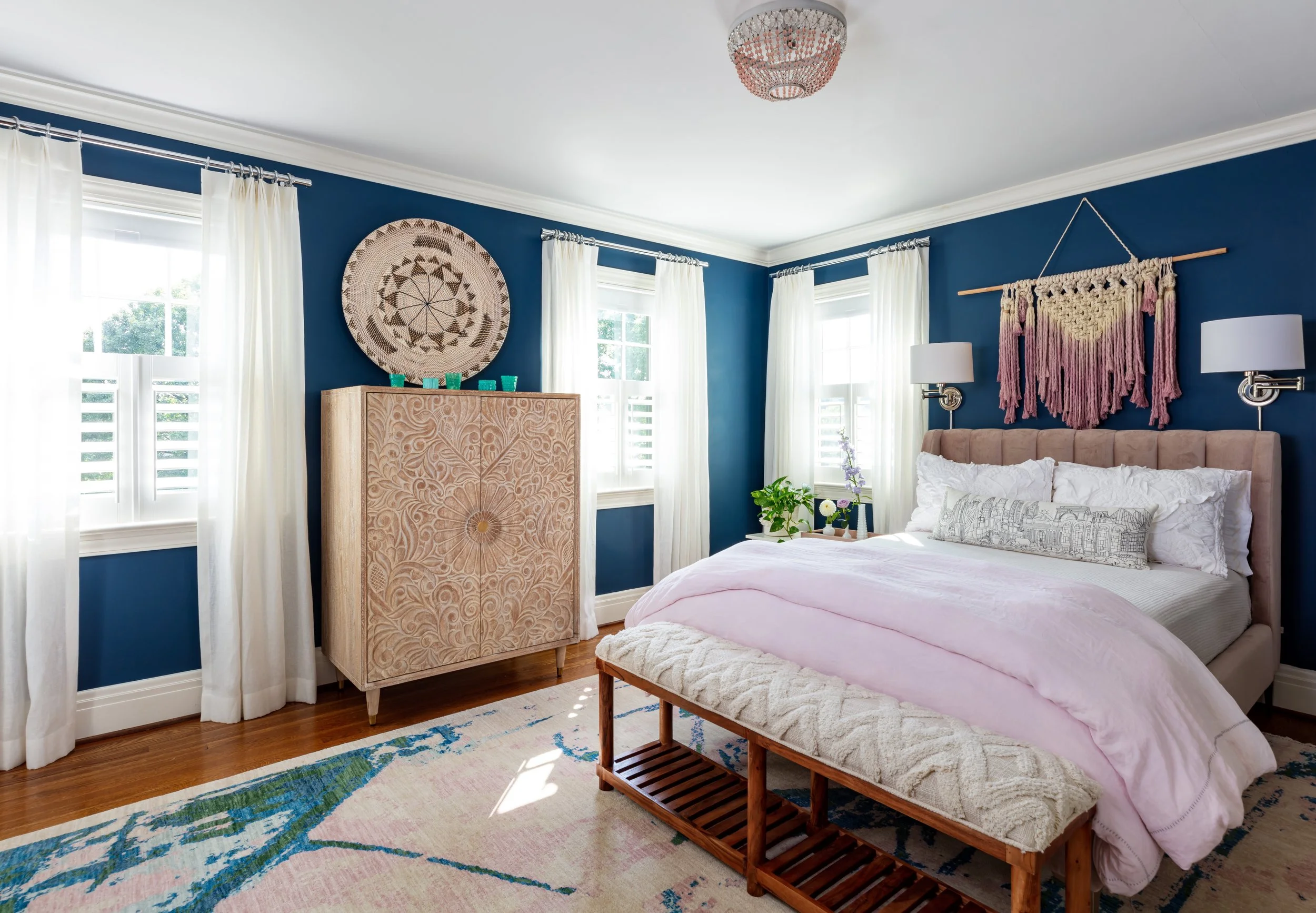 Elegant blue‑accented bedroom design featuring a pink bedspread, boho macramé wall hanging, and stylish wooden furniture for cozy home inspiration