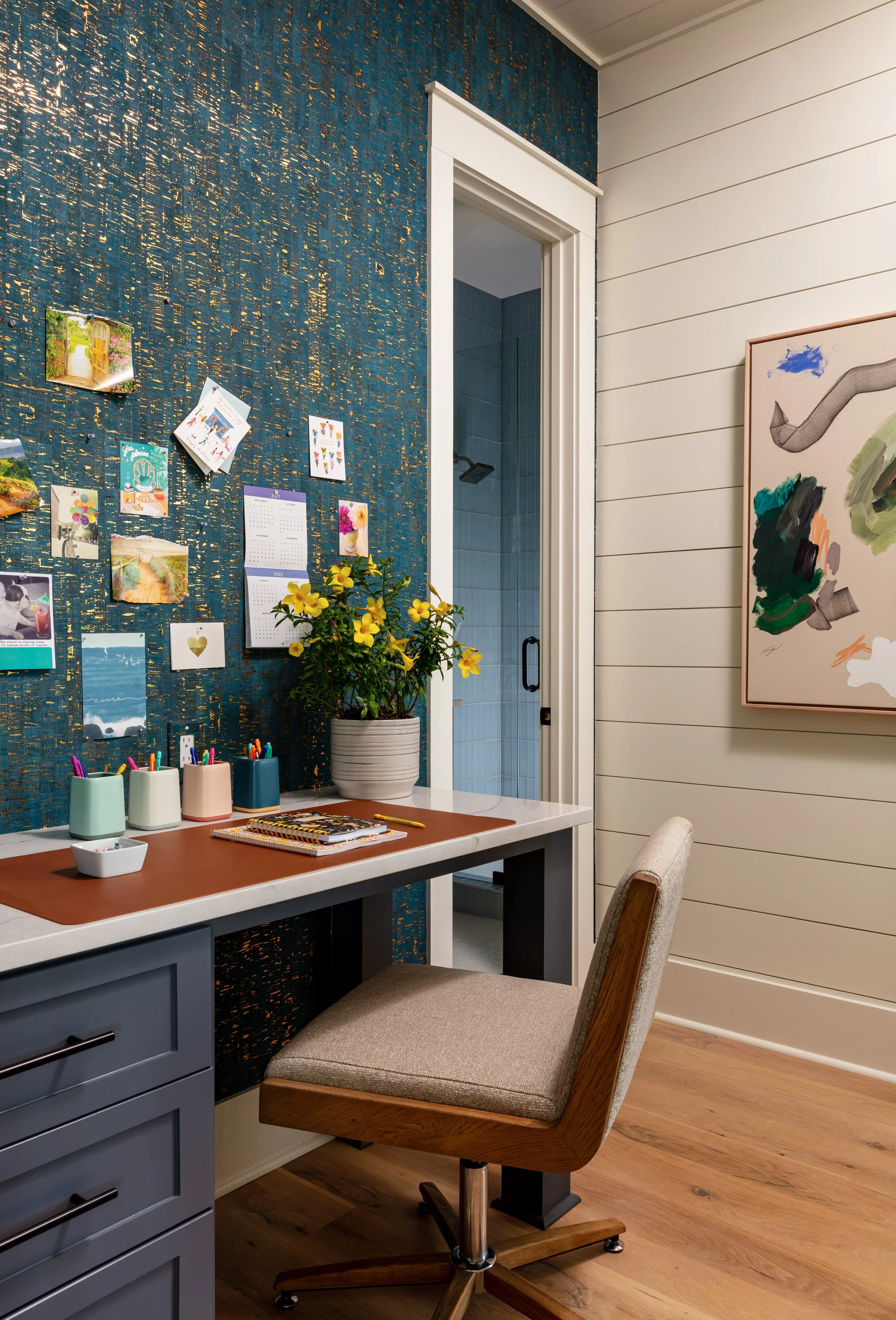 Stylish home office with teal gold-speckled wallpaper, white desk, yellow flowers, artwork on shiplap wall, inspiring workspace design for productivity and modern interior décor inspiration