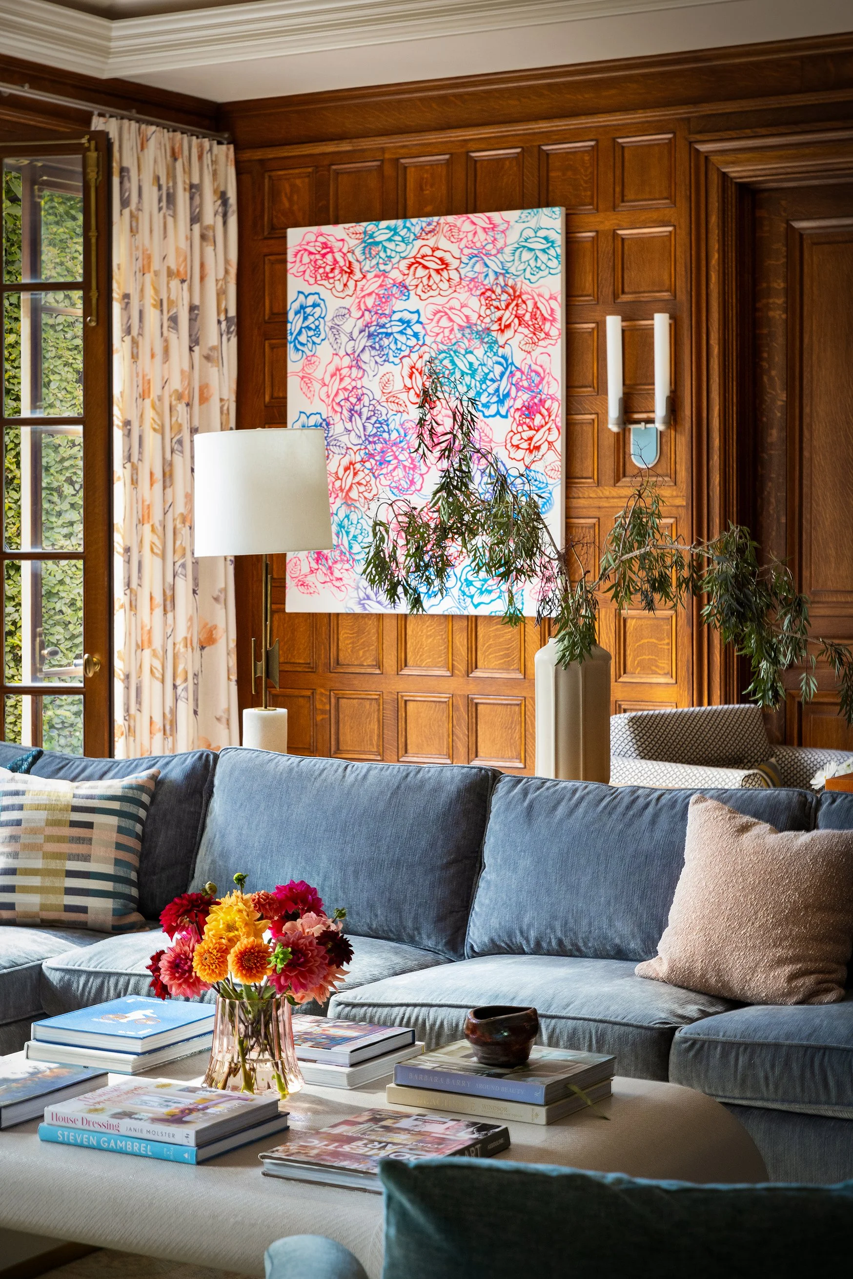 warm family room wood paneled walls blue sectional with colorful art lamps and sconces