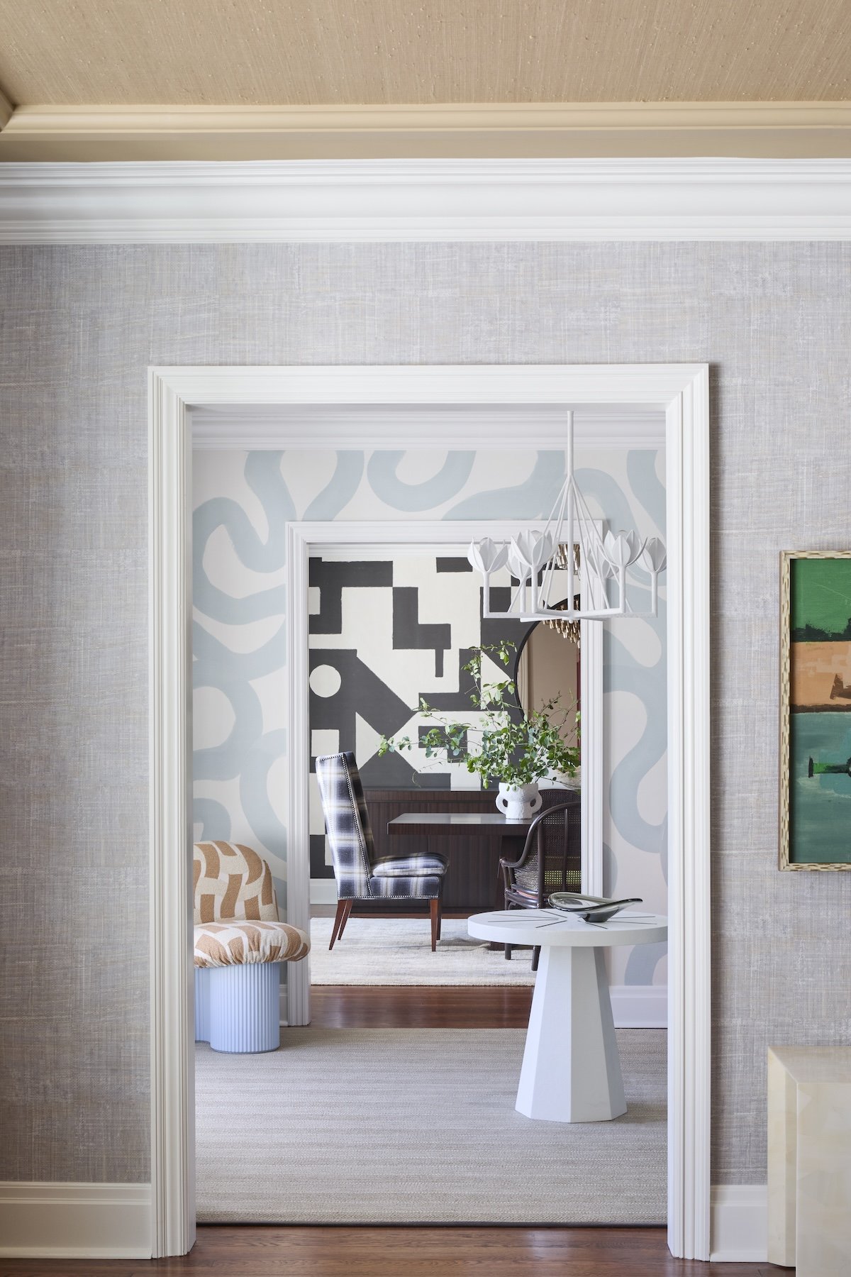 layered interior view through doorways with light blue squiggle wallpaper white lotus chandelier and bold black white geometric mural by betsy wentz