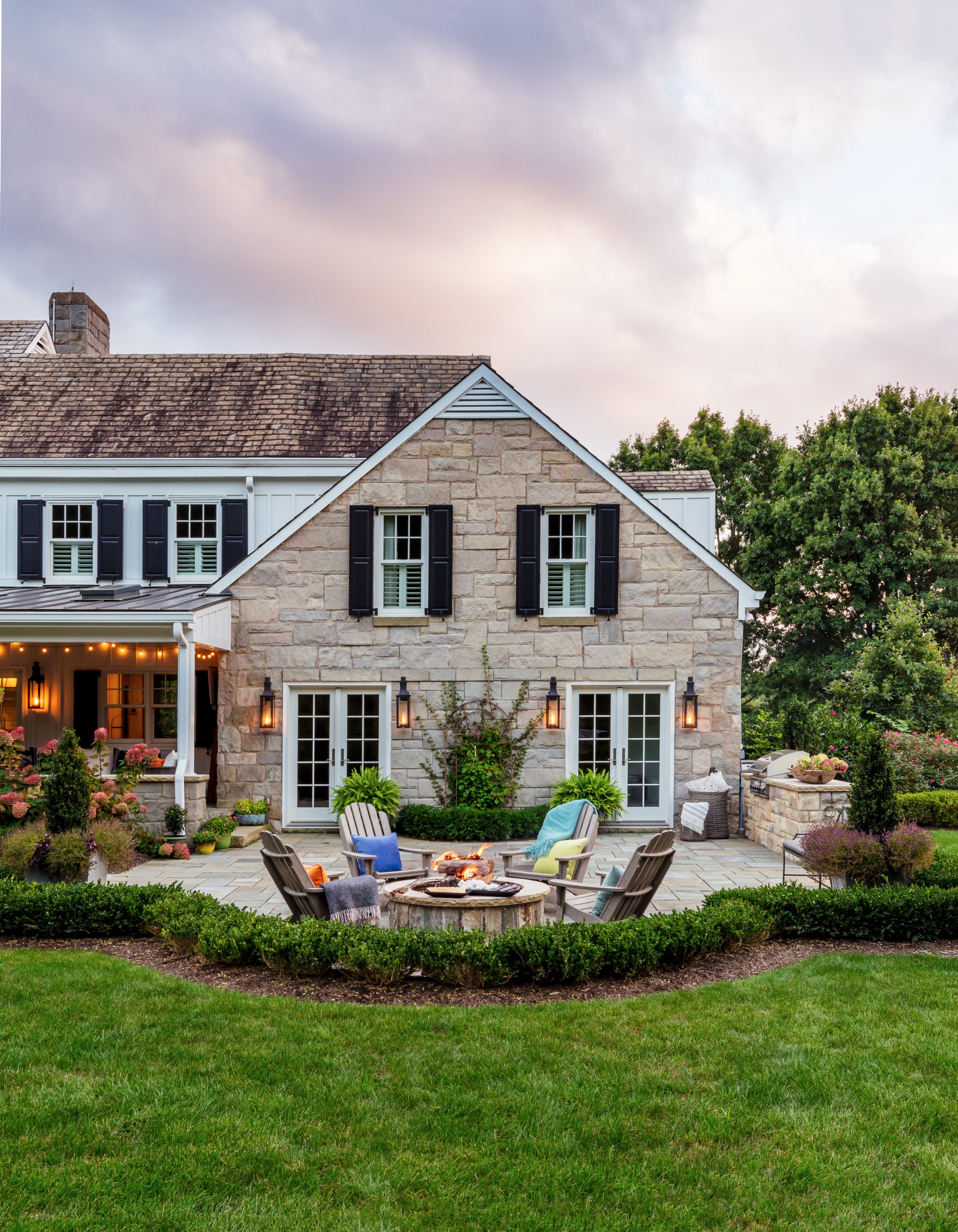 Elegant outdoor patio with chairs around fire pit string lights & lush greenery for stylish alfresco entertaining spaces modern home 