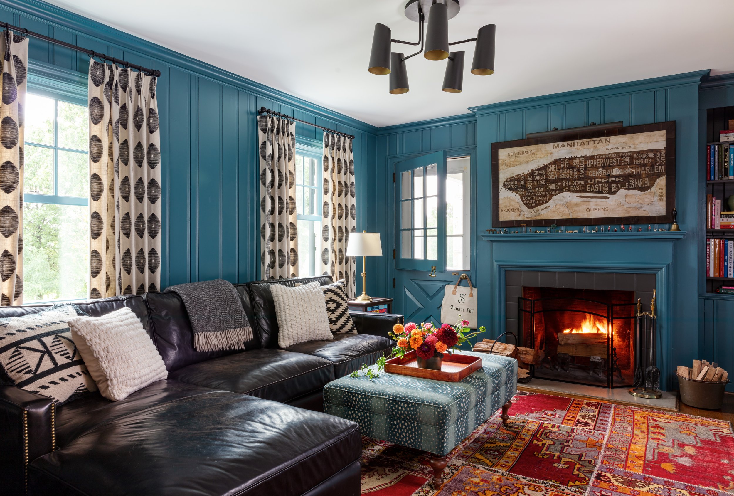 eclectic boho living room design with teal walls patterned rug black leather sofa modern art decor cozy fireplace vintage chic interior inspiration