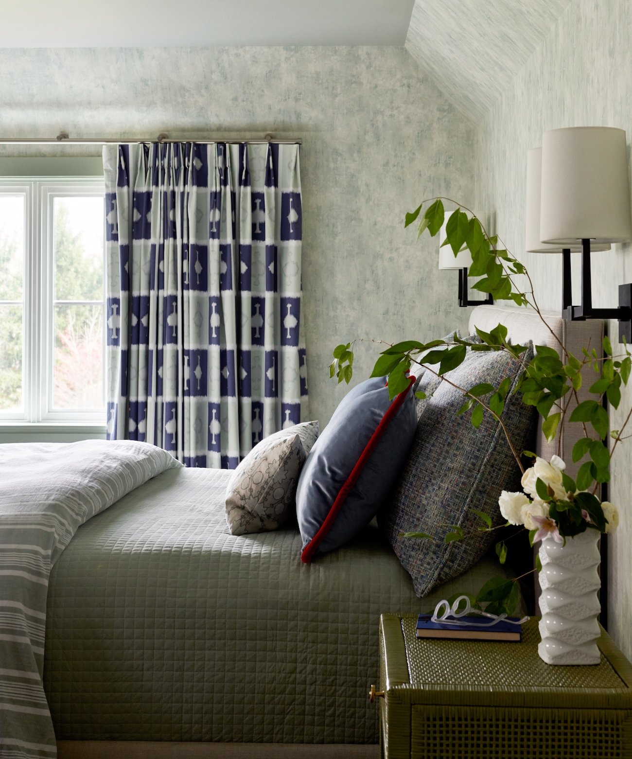 bedroom design textured wallpaper ikat curtains quilted bedspread sconces nightstand natural light