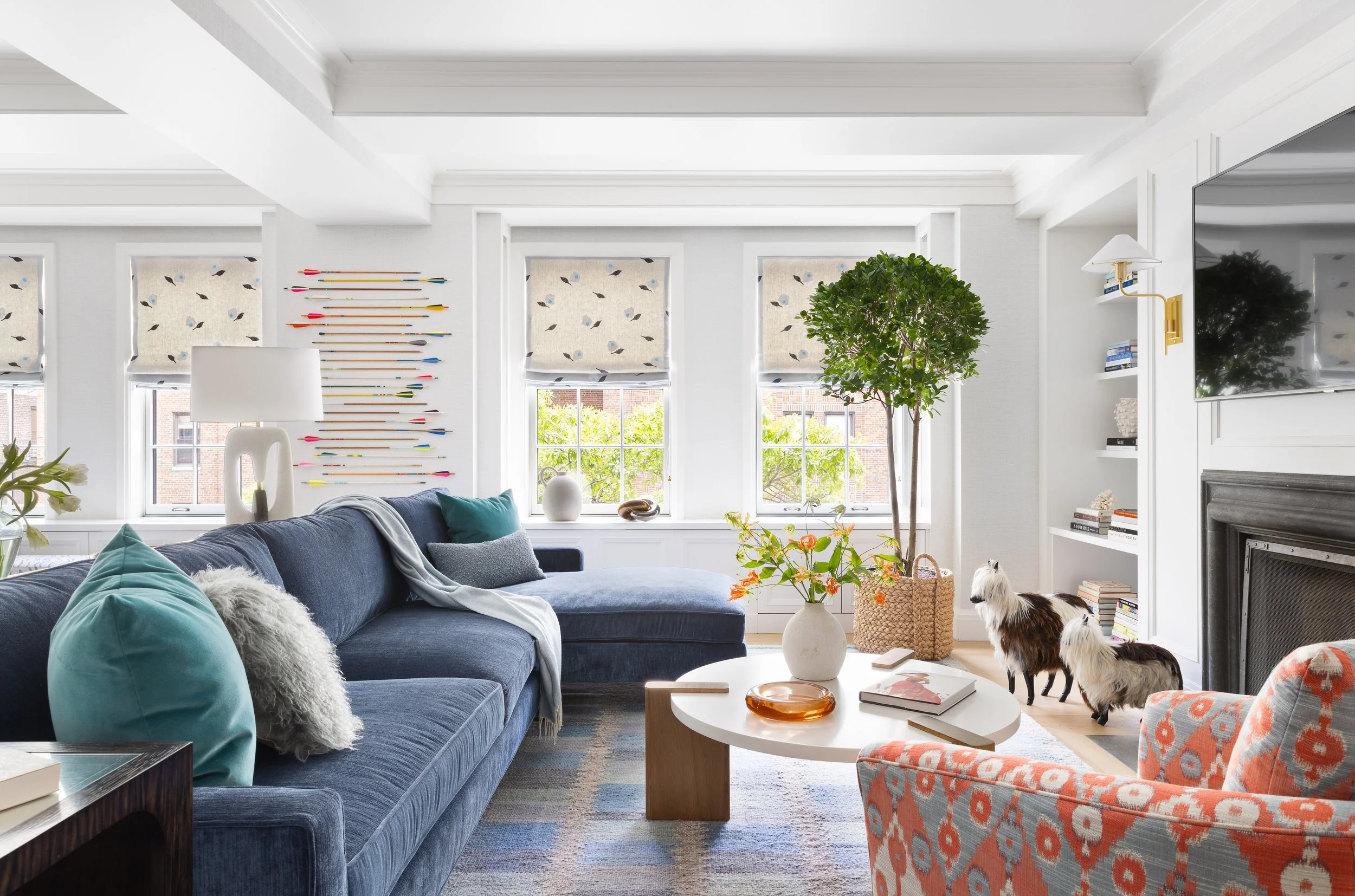 casual family room with blue sectional  fireplace with tv above and bookcase storage 