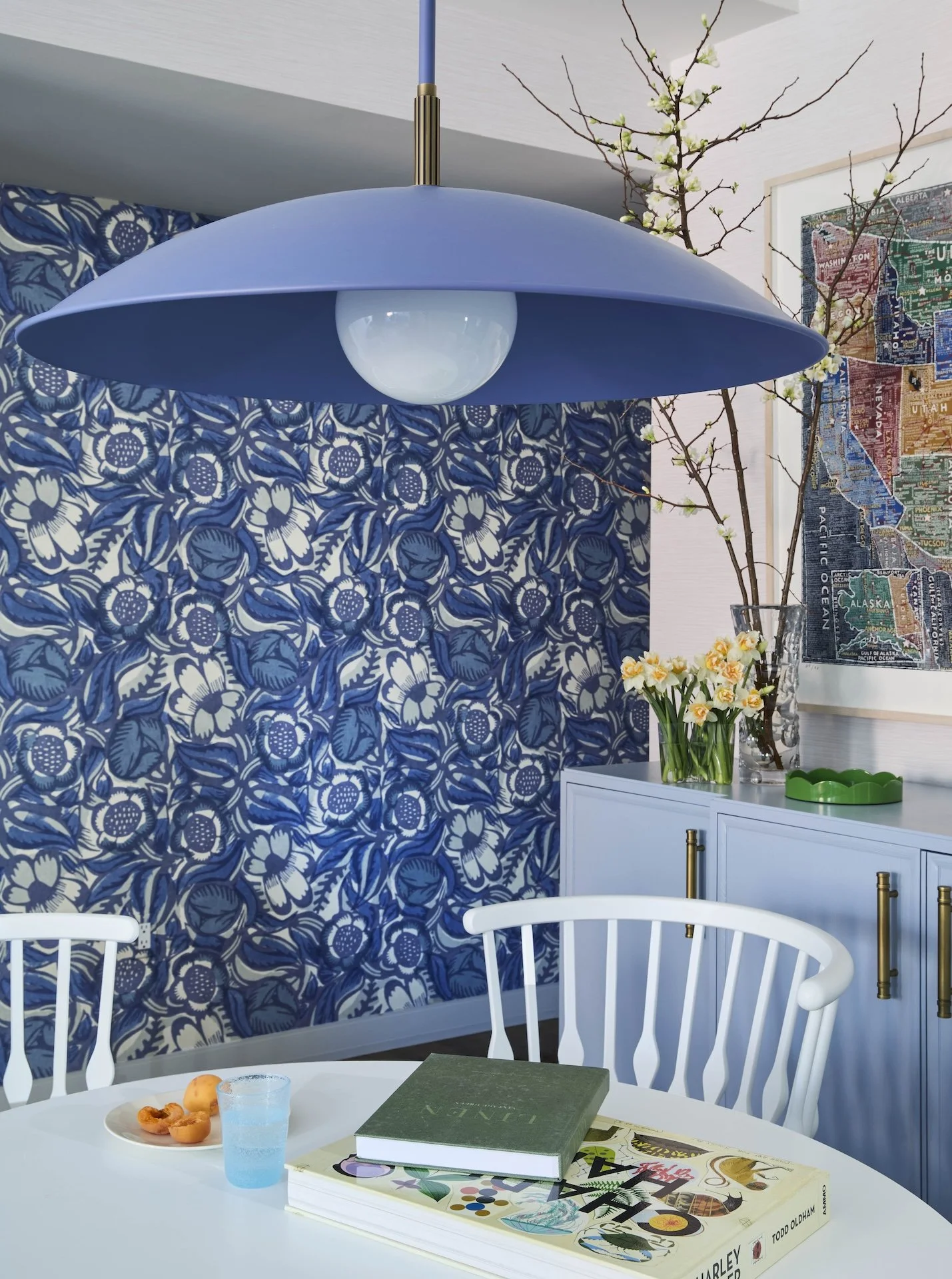 modern dining room blue pendant light bold floral wallpaper white table colorful art styled sideboard