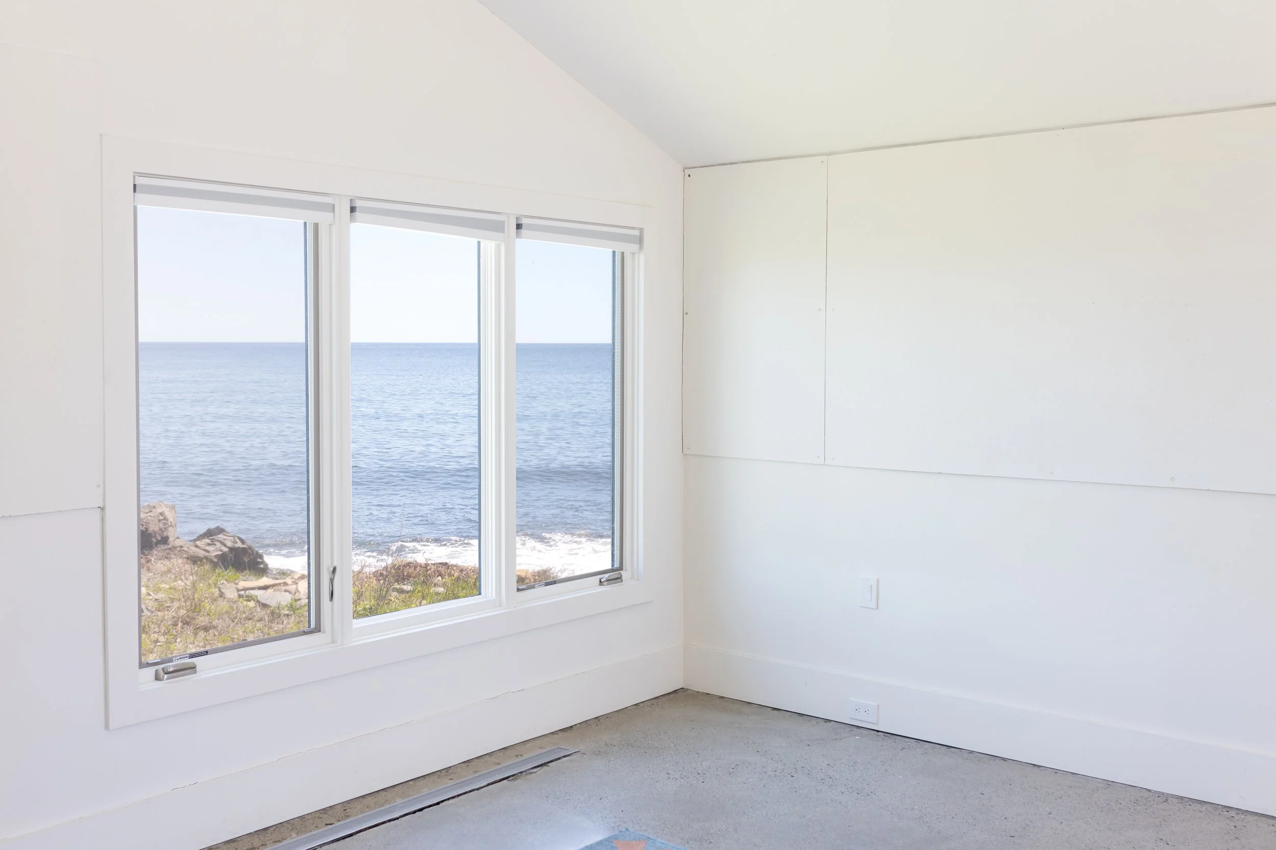 Interior room with white walls and a large window offering an ocean view.