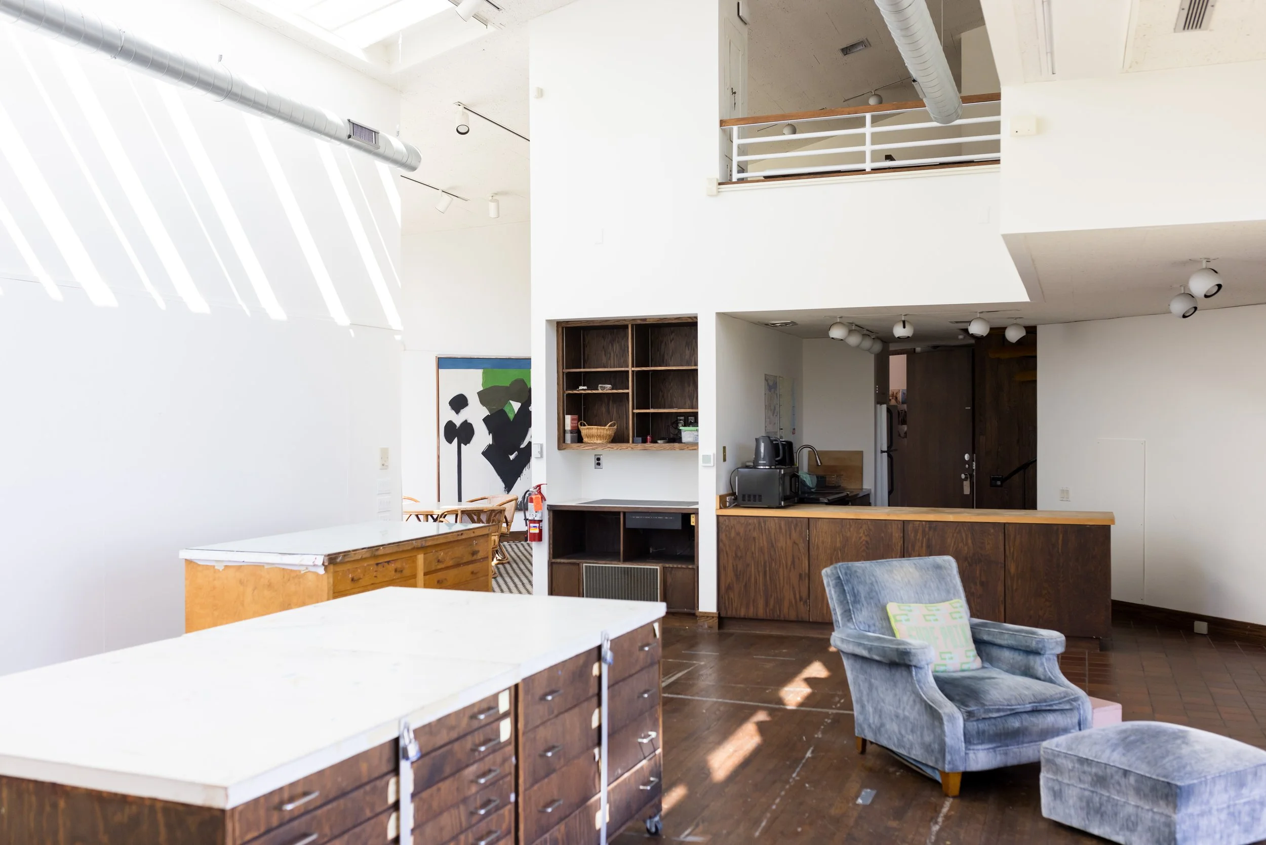 Interior of a modern living space with wood furniture, an armchair, and abstract wall art